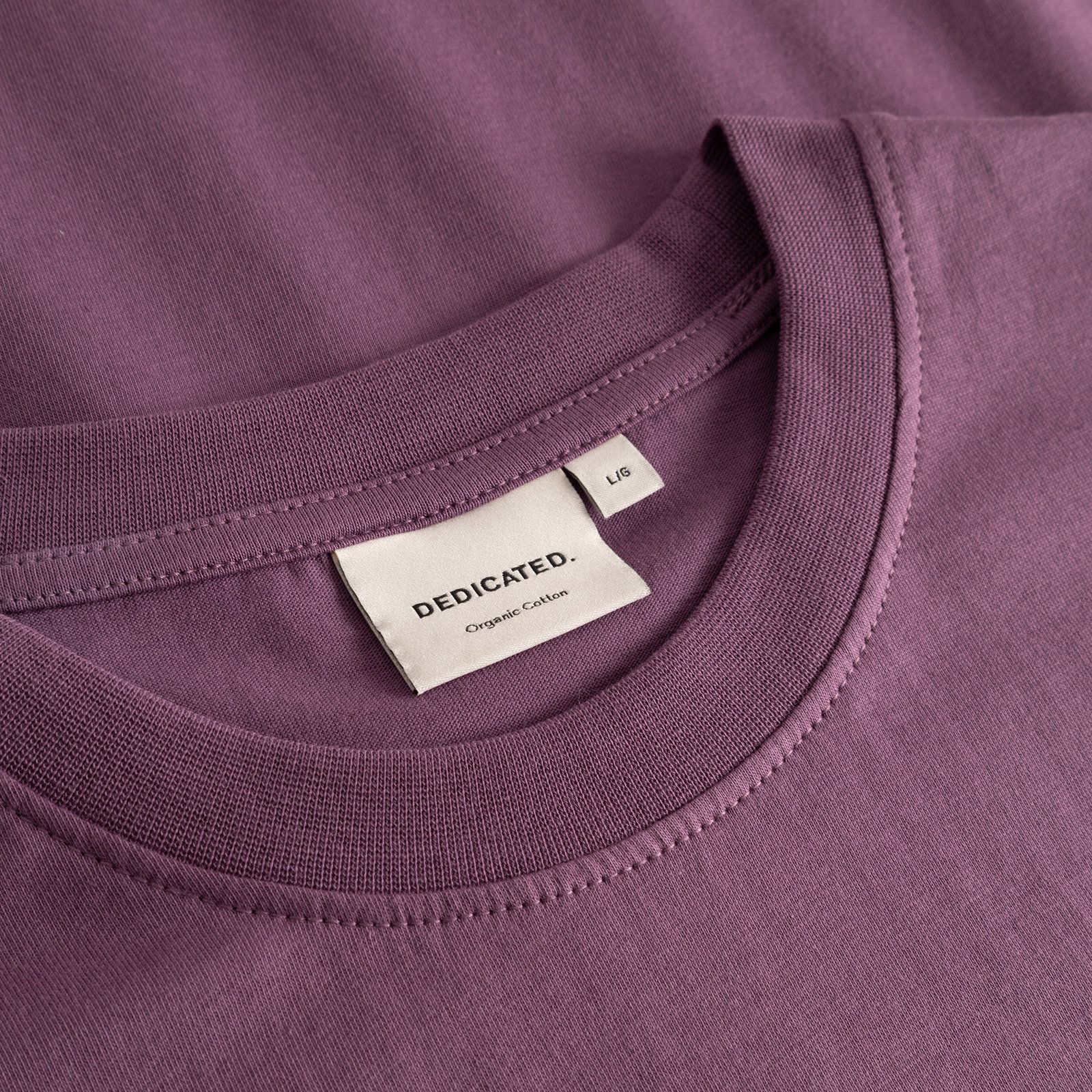 Närbild av den ribbade kragen och nacketiketten på T-shirt Stockholm Base i en bärlila nyans.