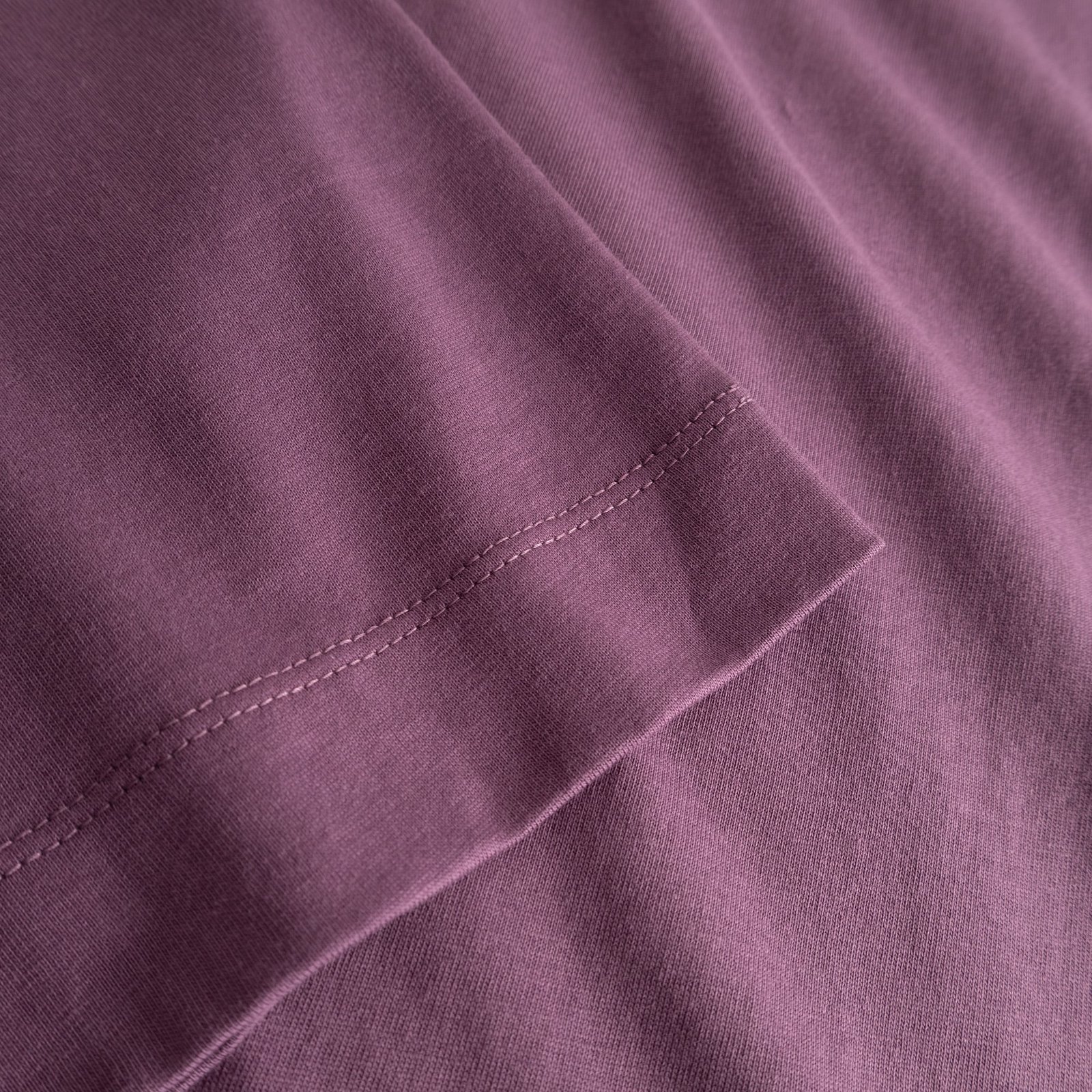 A close-up of the T-shirt Vadstena Base in Berry Purple highlighting the soft organic cotton and the sleeve's fine stitching.