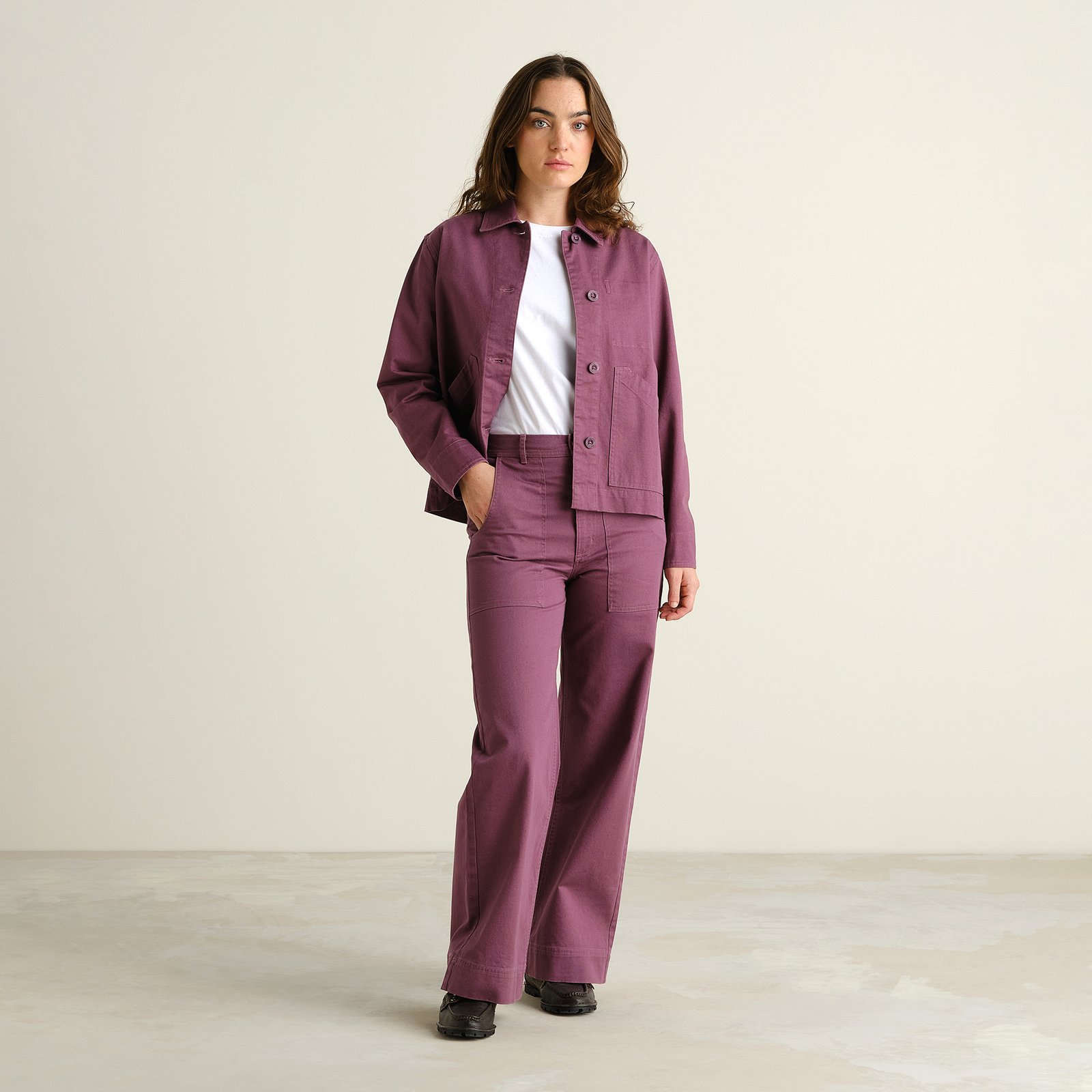 Modell i Workwear Pants Vara med vida ben i Berry Purple, med matchande jacka och vit t-shirt.