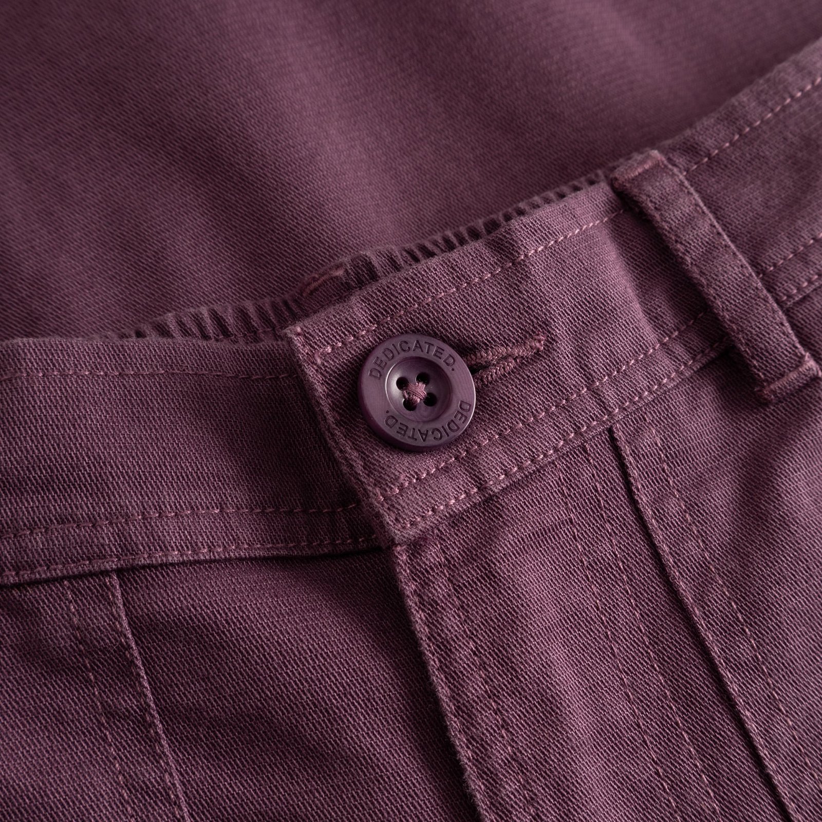 Detaljbild på Workwear Pants Vara i Berry Purple som visar dobby ripstop-tyget och den specialdesignade Dedicated-knappen.