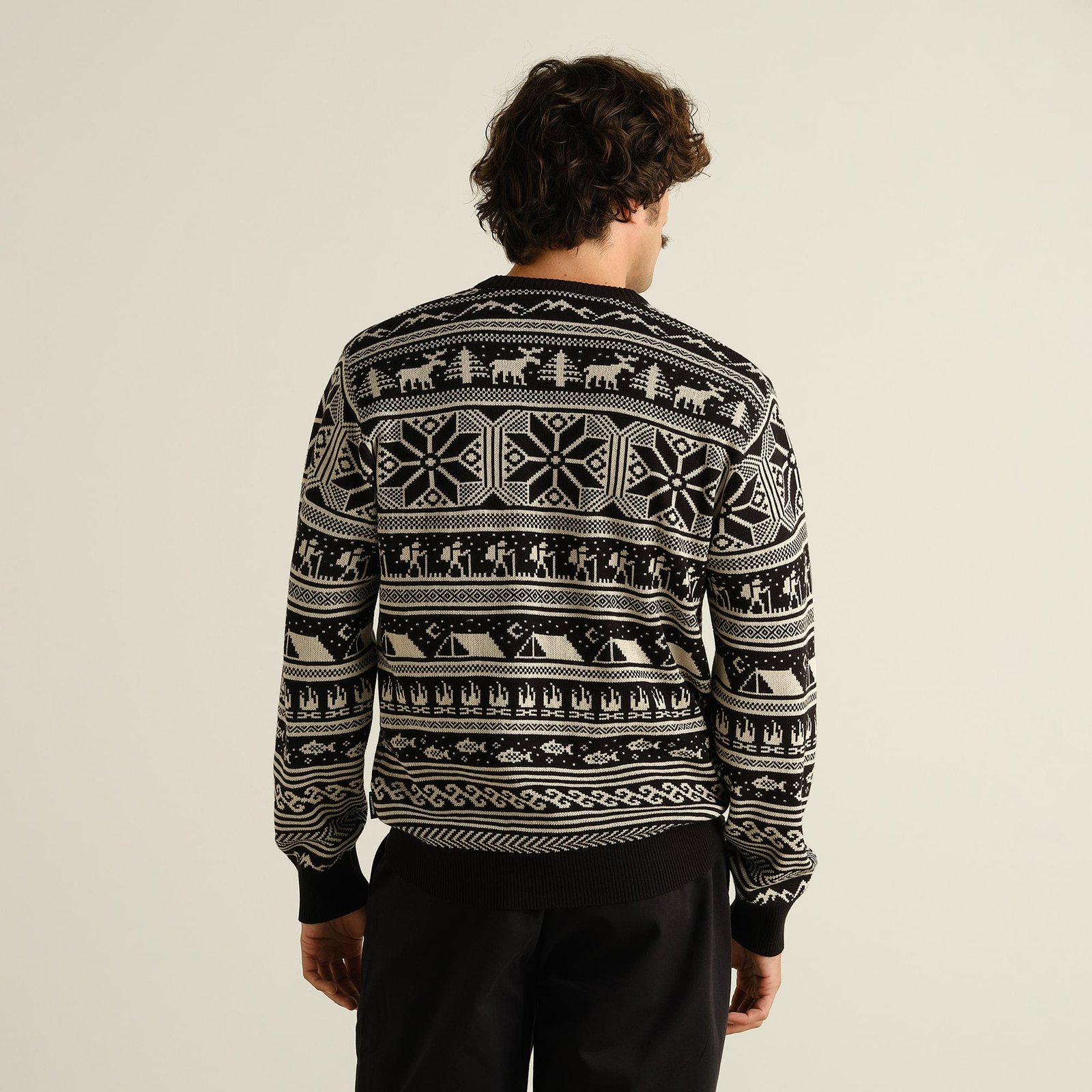 Model from the back wearing the black Sweater Mora Fairisle Hike, showing off its unique pattern of hikers, moose, and tents.