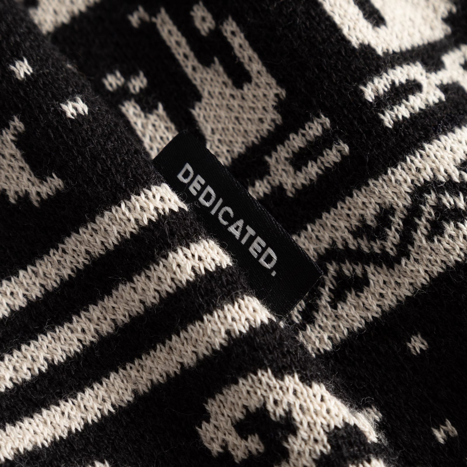 Close-up shot of the Cardigan Delsbo Fairsle Hike, detailing its jacquard knit pattern and the Dedicated brand label.