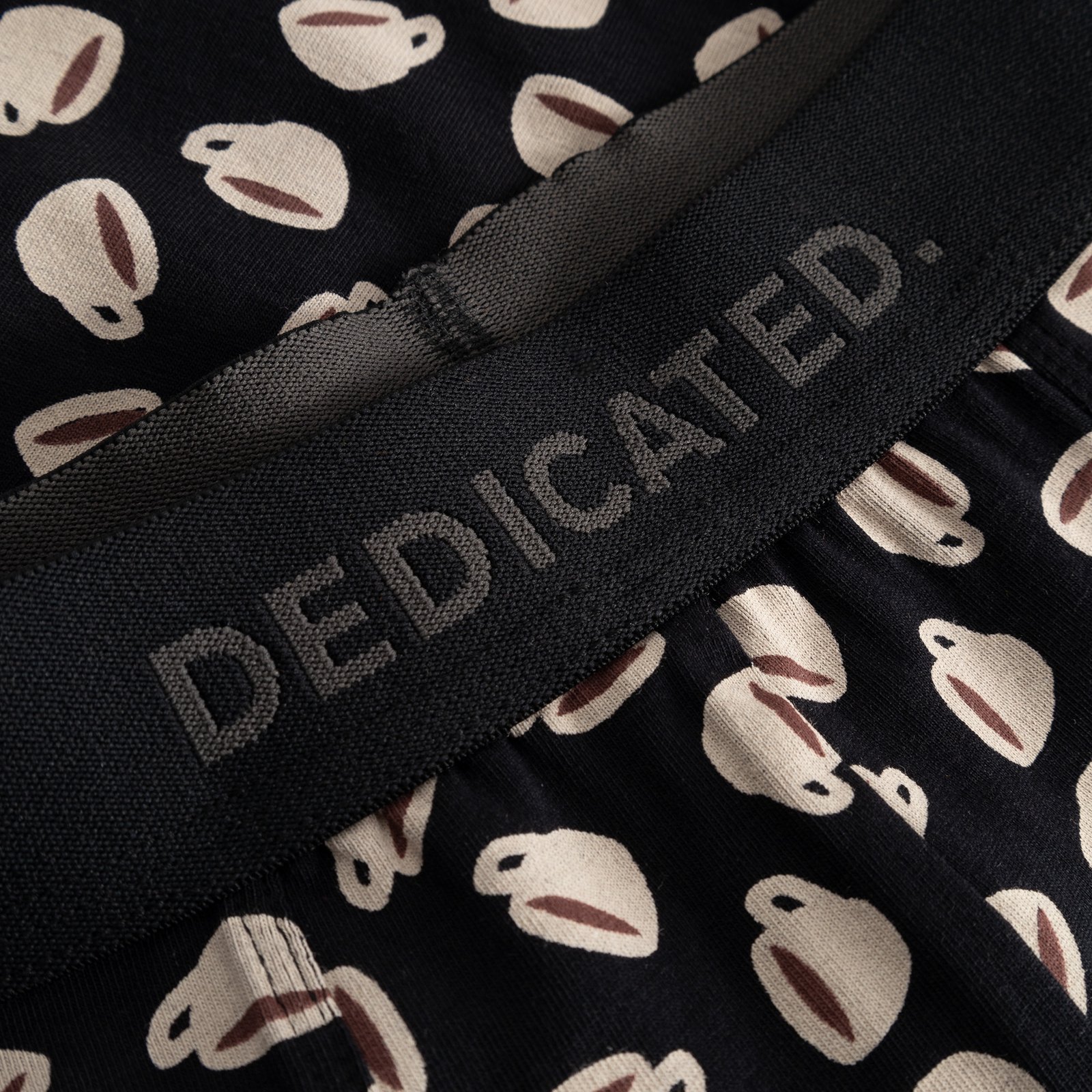 Detailed shot of the black Dedicated logo waistband on the Kalix boxer briefs with their fun coffee cup print.