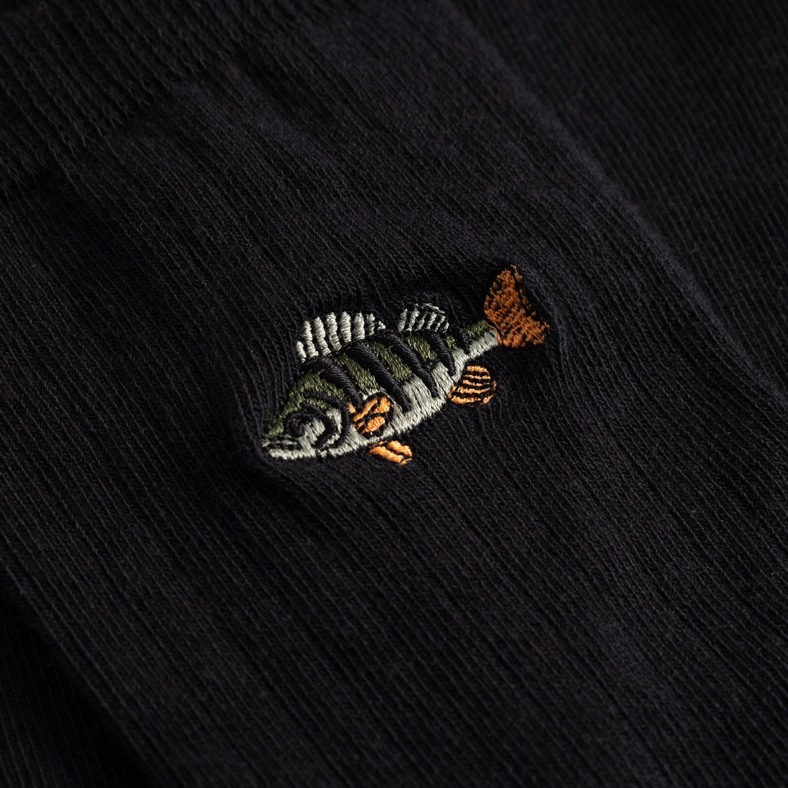 A close-up view of the fine perch embroidery on the black ribbed Knivsta socks.