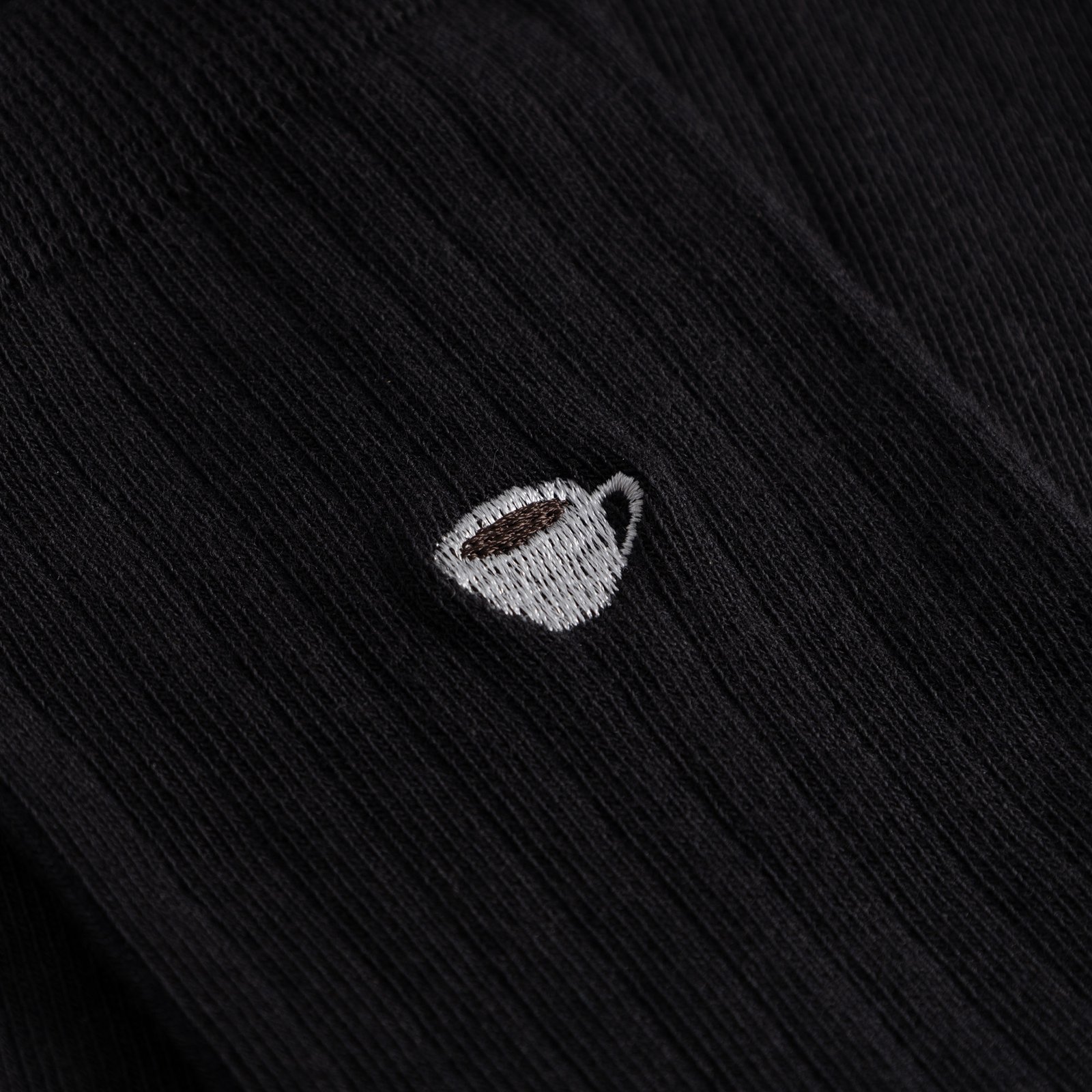 Close-up of the charming coffee cup embroidery on the black ribbed Knivsta socks.