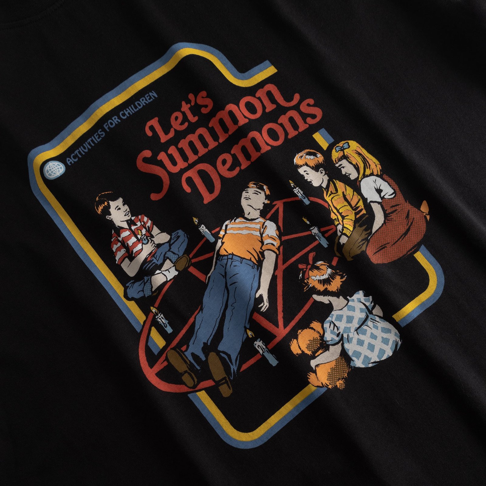 Close-up of the retro 'Let's Summon Demons' print by Steven Rhodes on a black t-shirt.