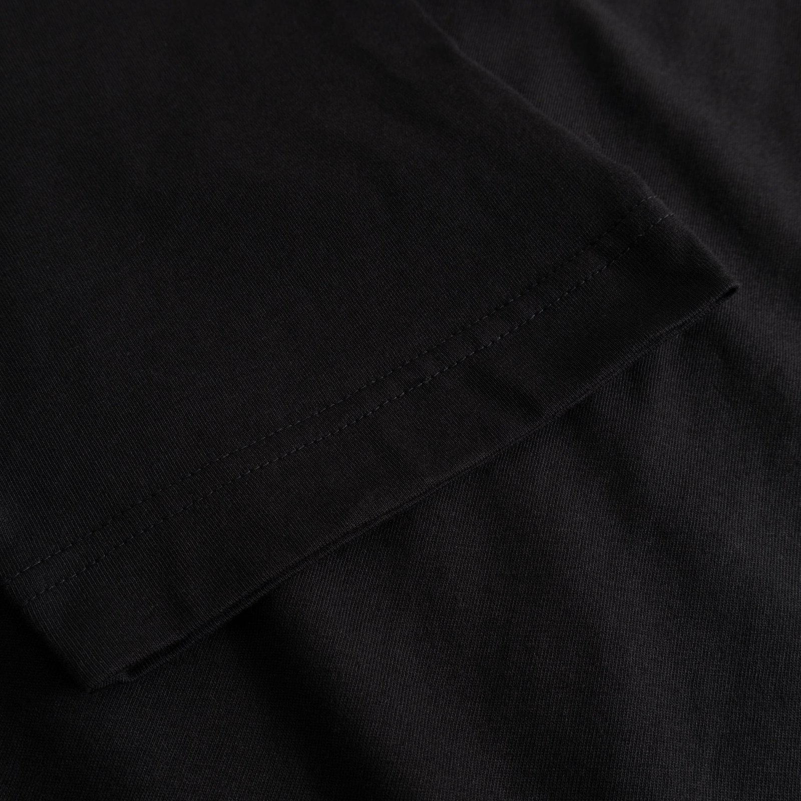Close-up of the sleeve hem on the black organic cotton T-shirt Vadstena, highlighting the double-needle stitching detail.