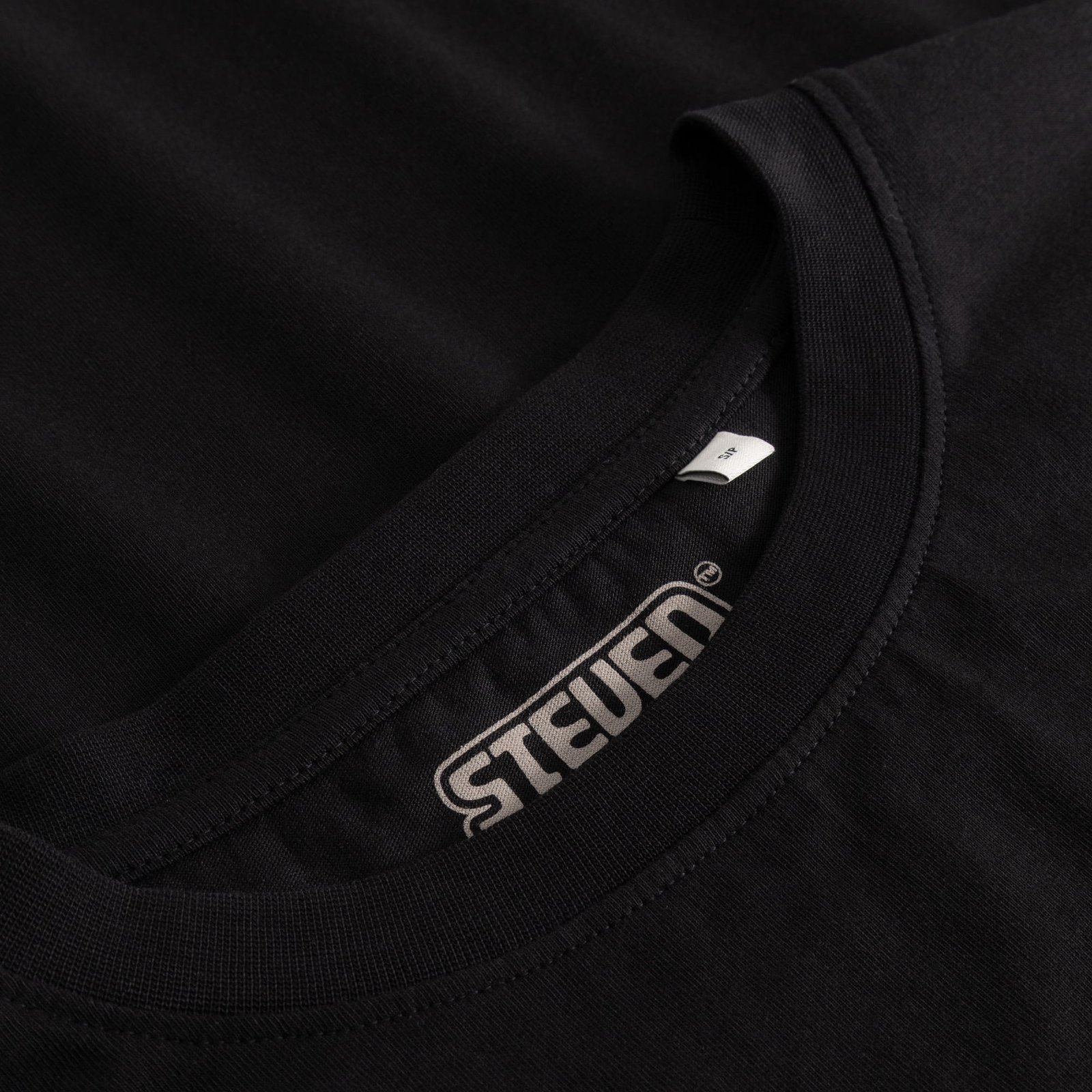 Close-up of the ribbed collar and the printed Steven Rhodes logo inside the black T-shirt Vadstena.