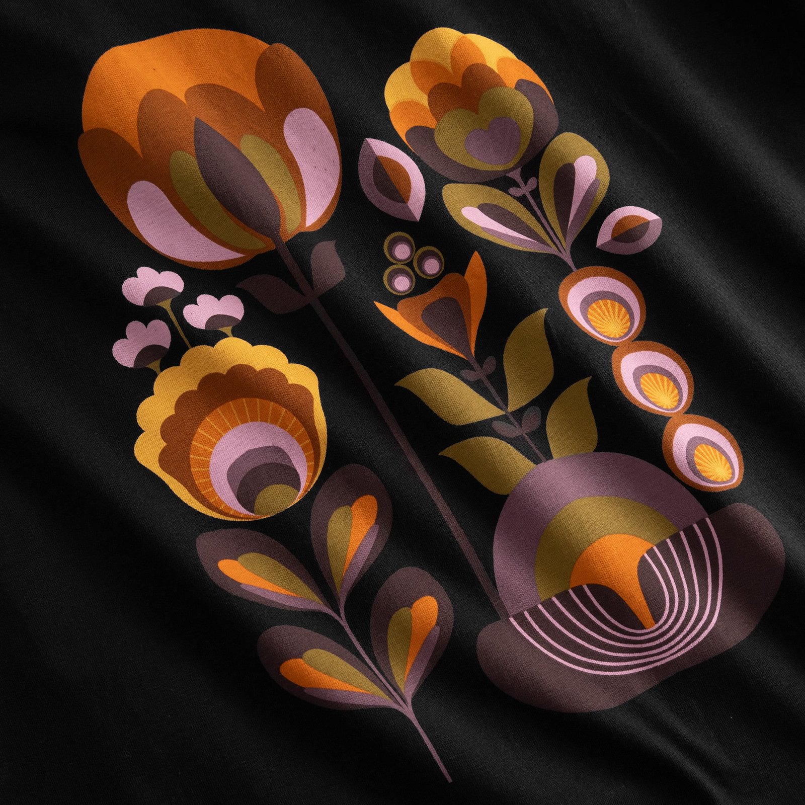 Detailed shot of the Vadstena T-shirt's Autumn Harvest print, featuring stylized florals in warm, retro colors.