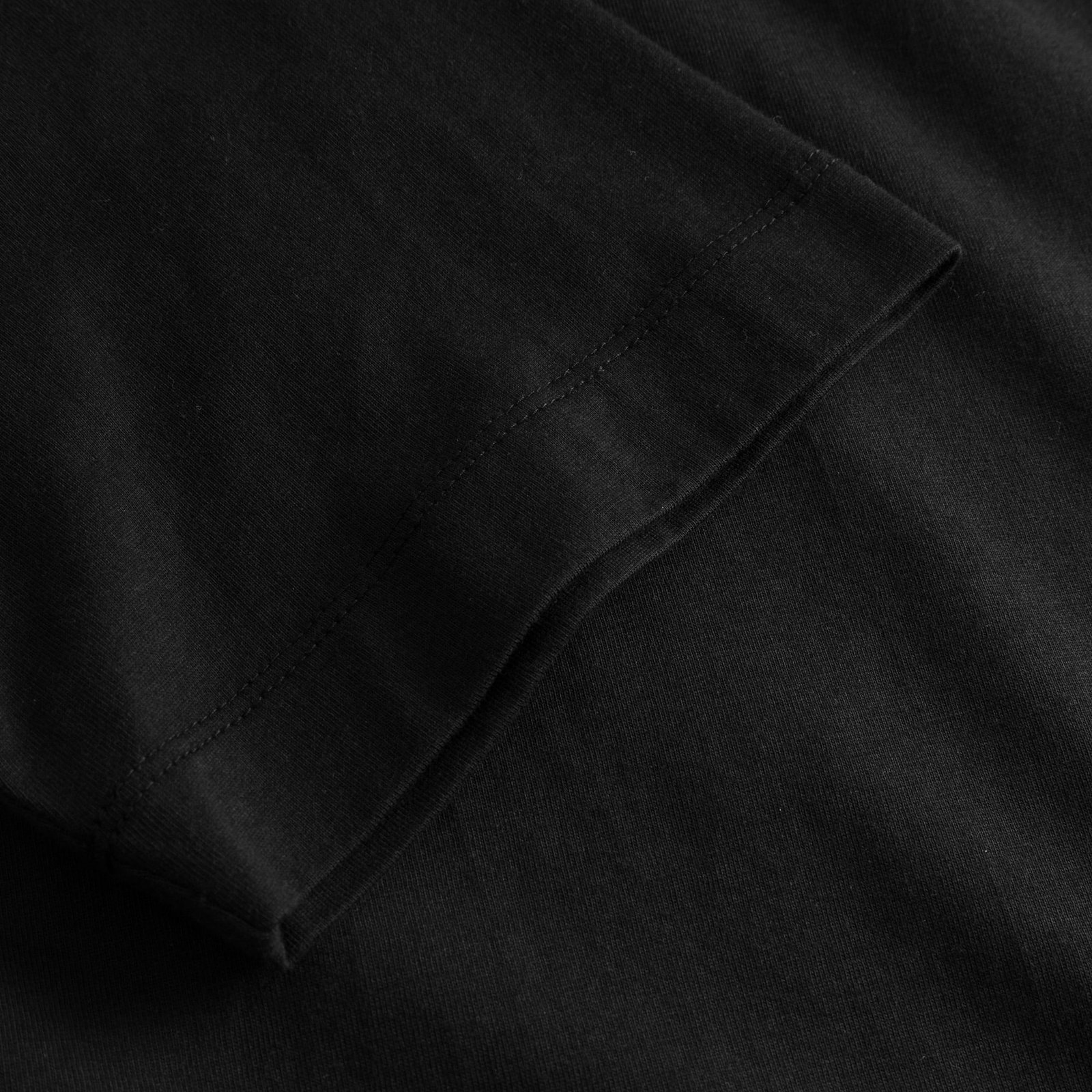 Close-up of the sleeve on the black T-shirt Vadstena Autumn Harvest, showing the soft organic cotton and fine stitching.