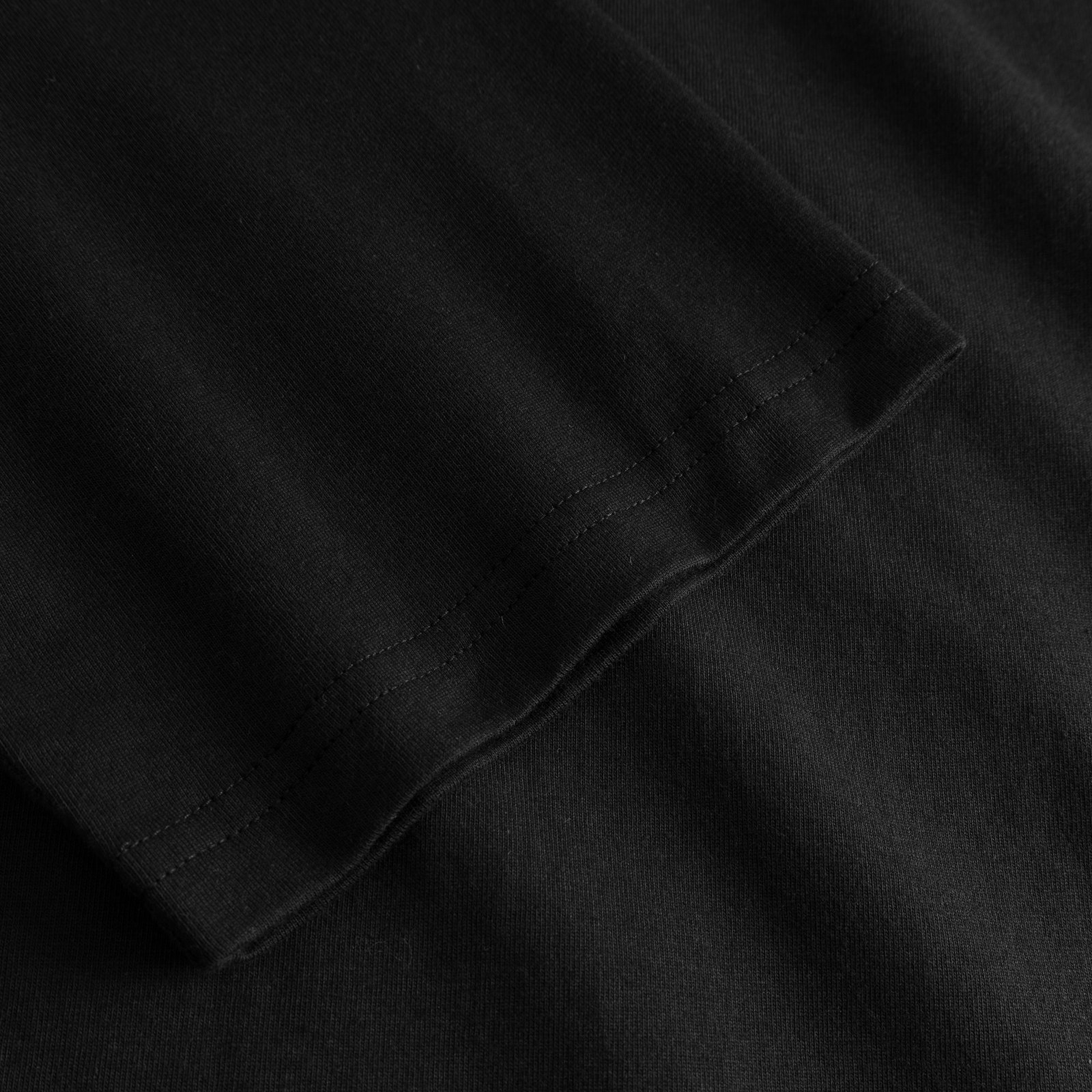 Close-up of the sleeve on the T-shirt Vadstena Painted Swans Black, showing the soft organic cotton fabric and neat hem.