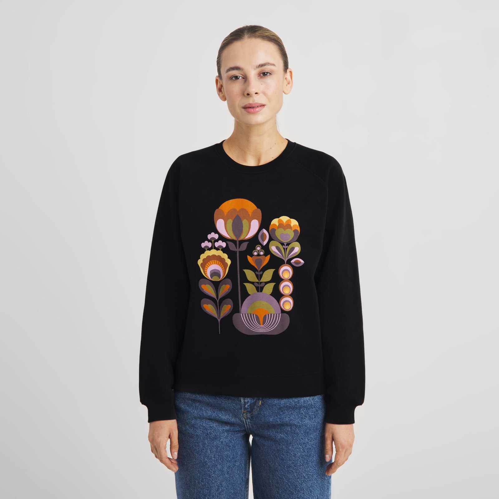 A model wears the black Sweatshirt Ystad with its stylized Autumn Harvest floral graphic, styled with classic blue jeans.