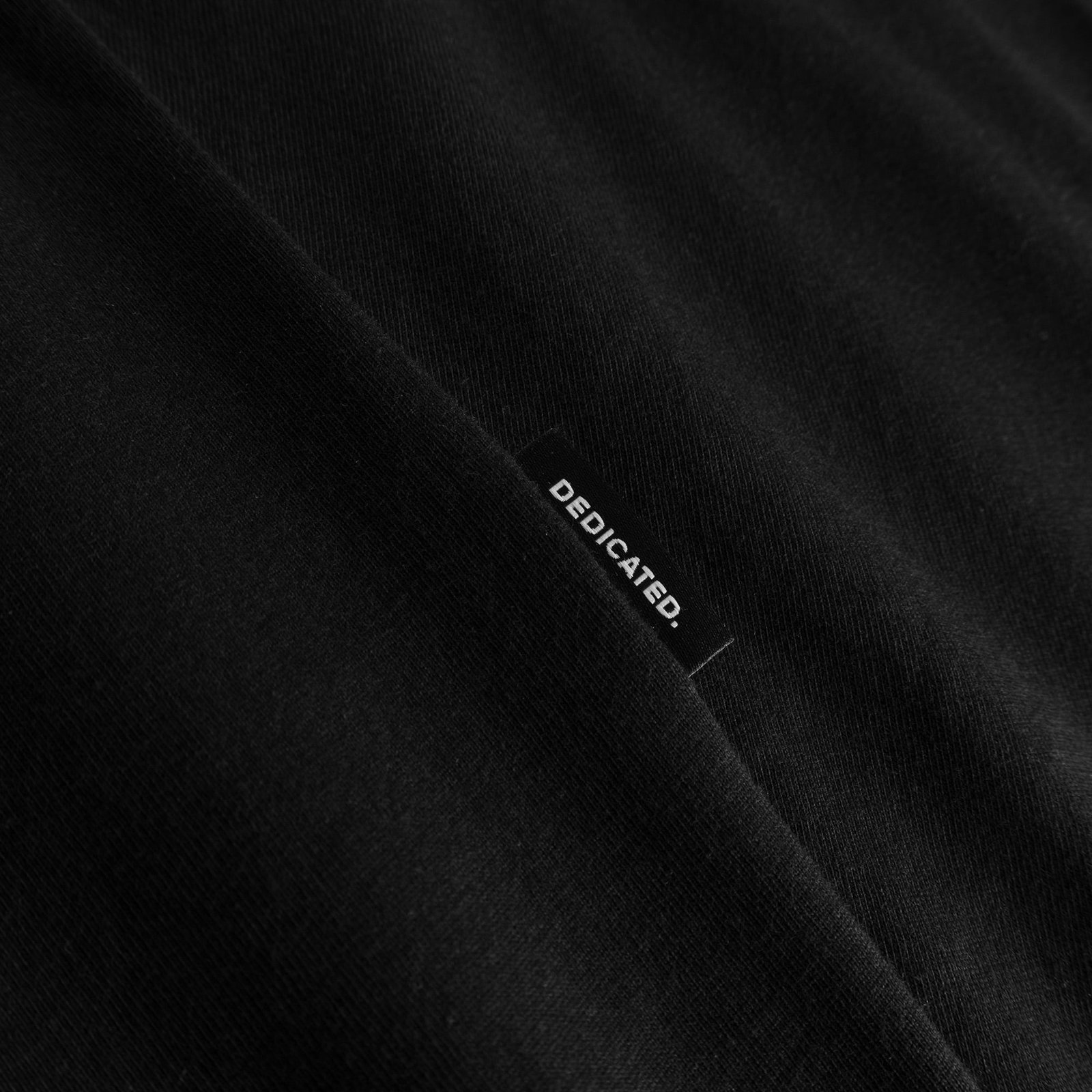 Nahaufnahme des Dedicated-Markenetiketts auf dem T-Shirt Stockholm Life in Schwarz.