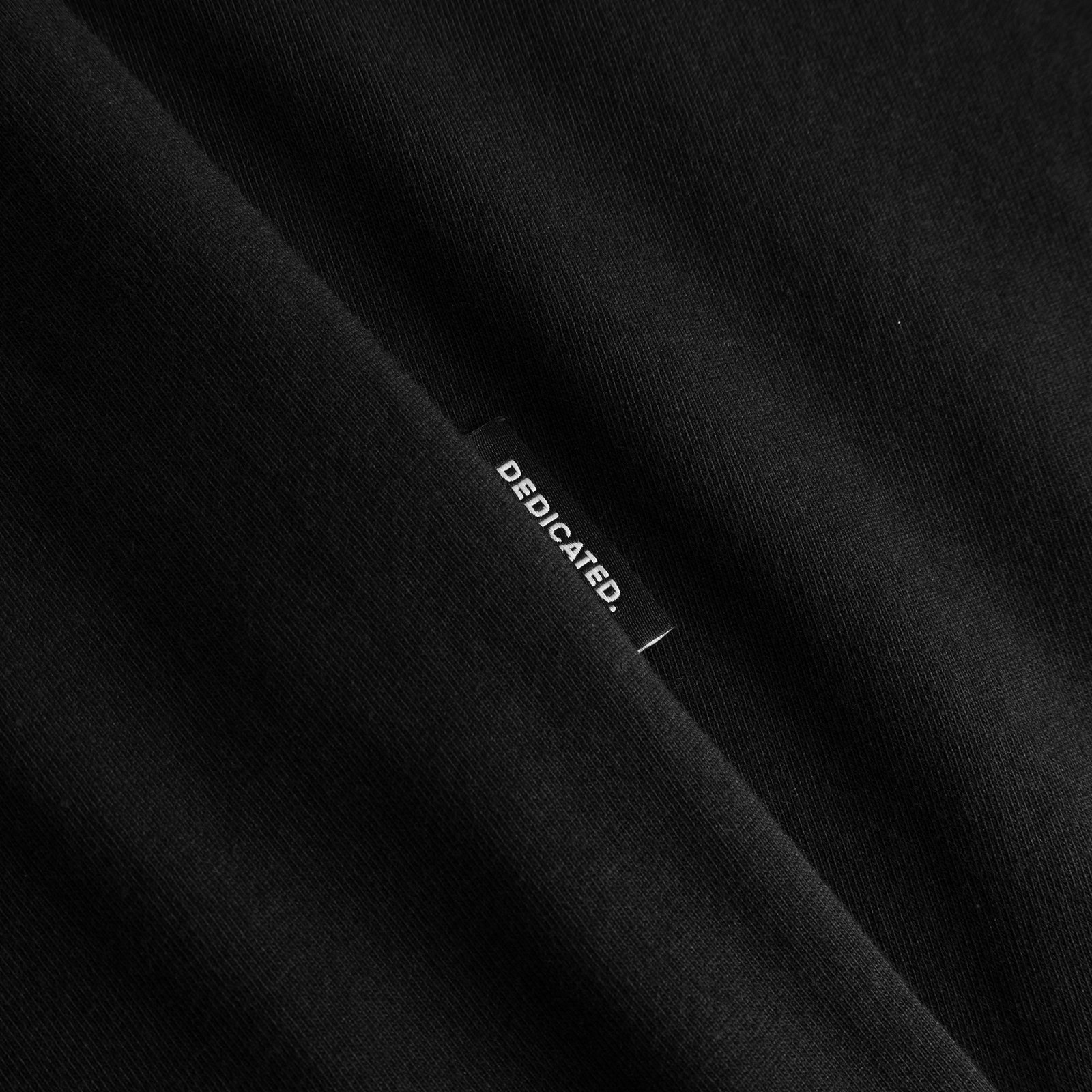 A close-up shot of the black T-shirt Stockholm Cat And Noodles, highlighting the soft fabric and signature Dedicated label.