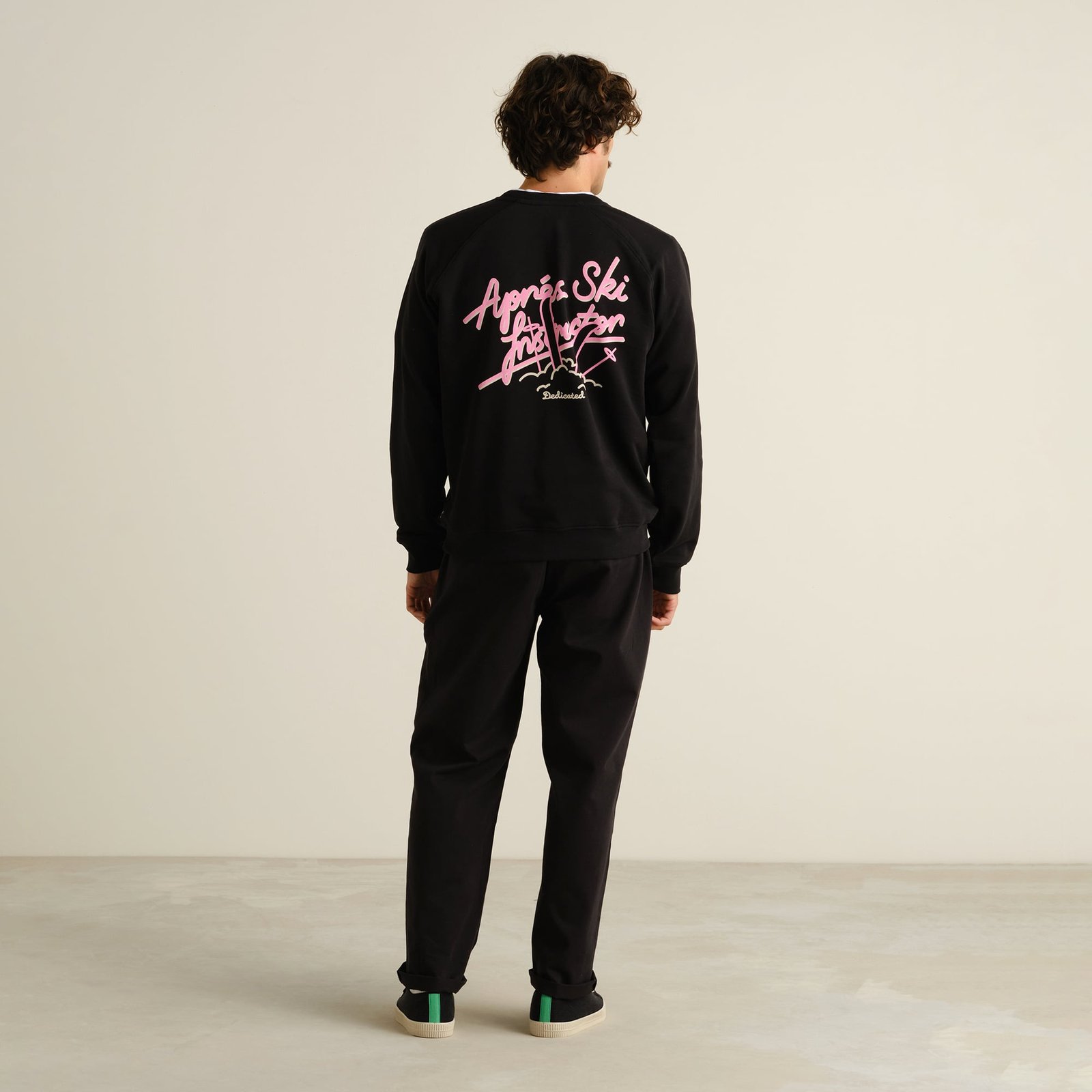 A model seen from the back wears the black Sweatshirt Malmoe with its playful pink 'Après Ski Instructor' graphic.