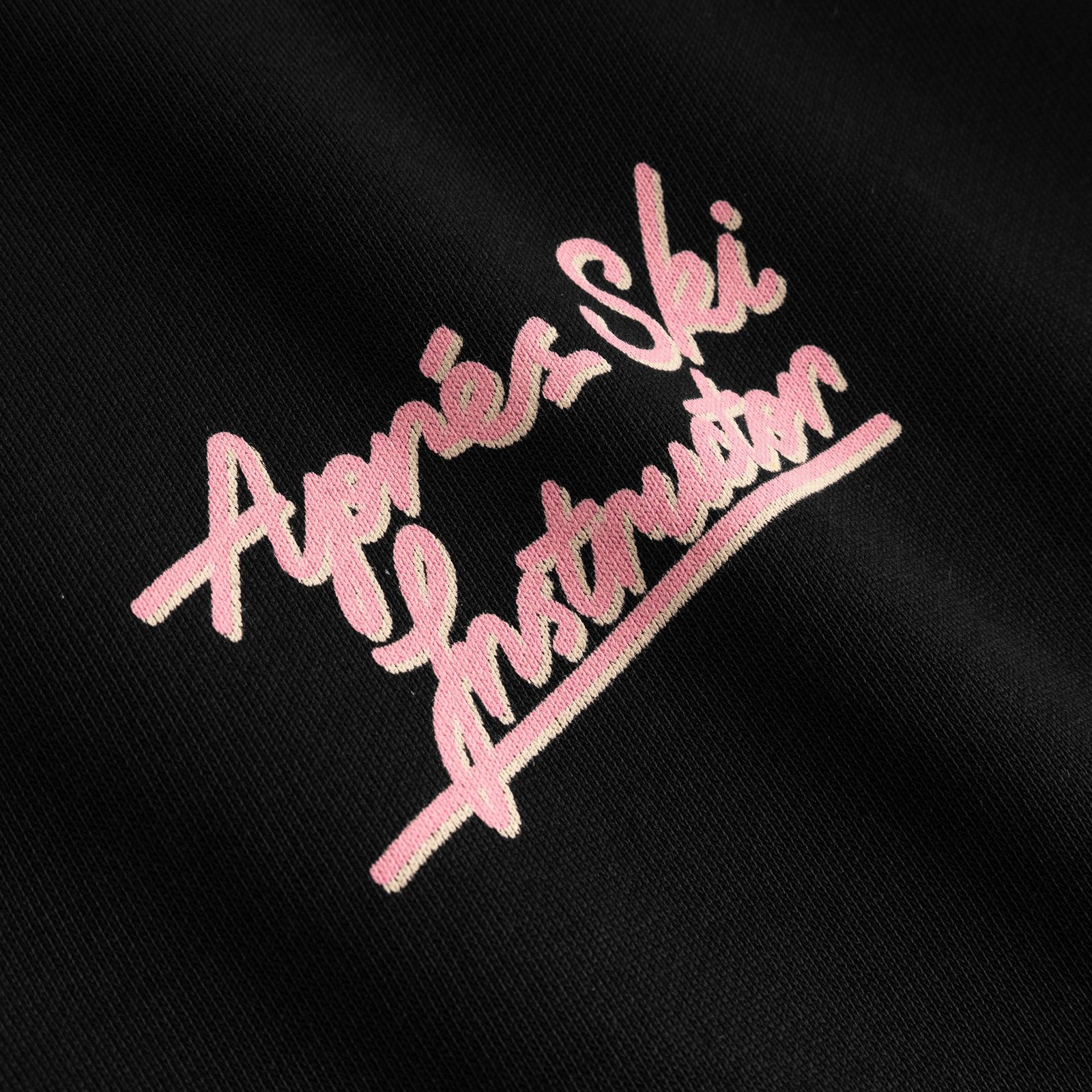 A close-up of the playful pink 'Après-Ski Instructor' embroidery on our black Malmoe sweatshirt.