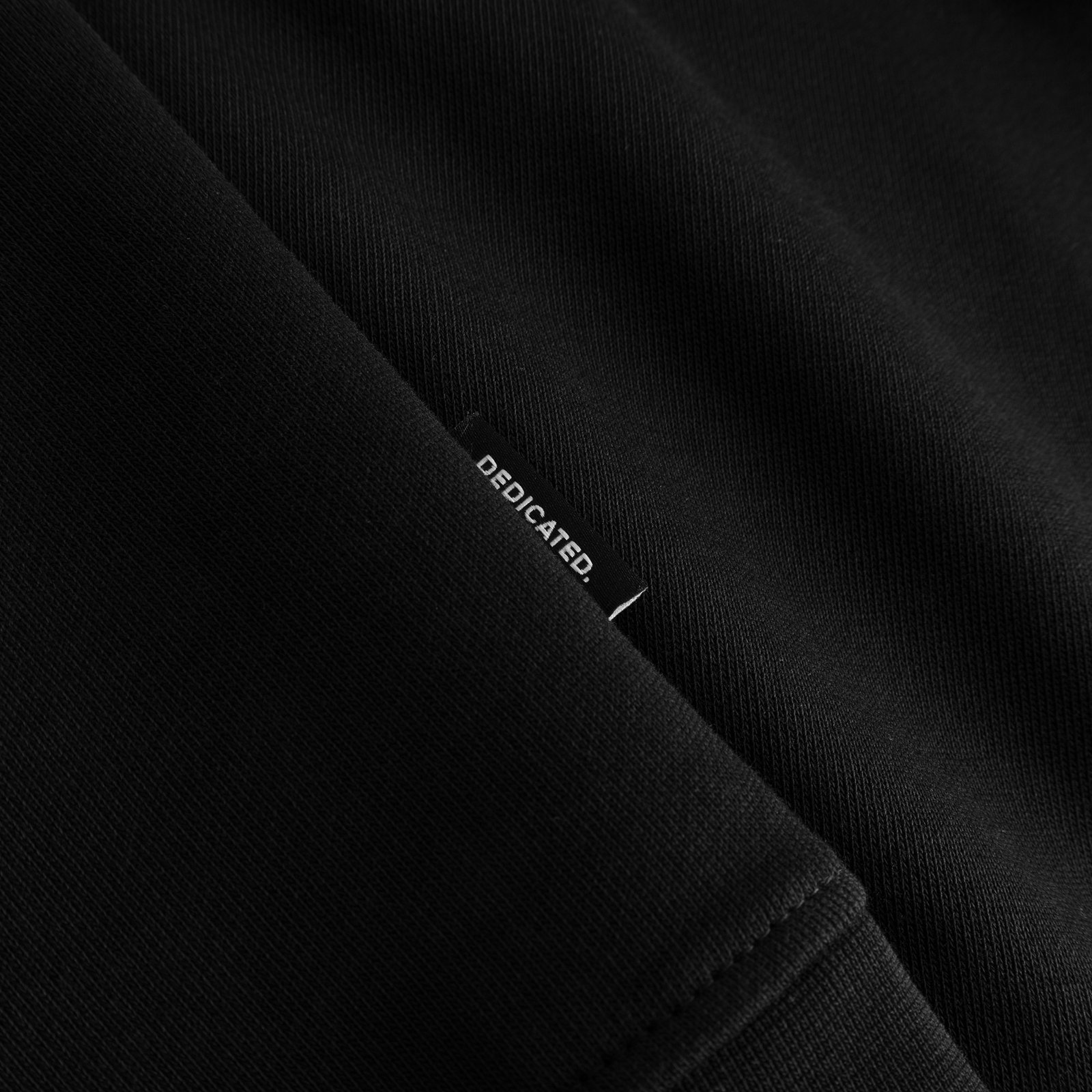 Close-up detail of the black Sweatshirt Malmoe, highlighting the signature Dedicated brand tab at the hem.