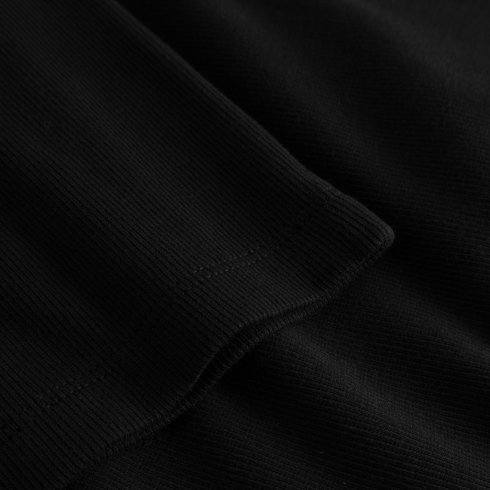 Nahaufnahme des Rippstoffs und des Ärmelbündchens am schwarzen Kleid Lunsen.