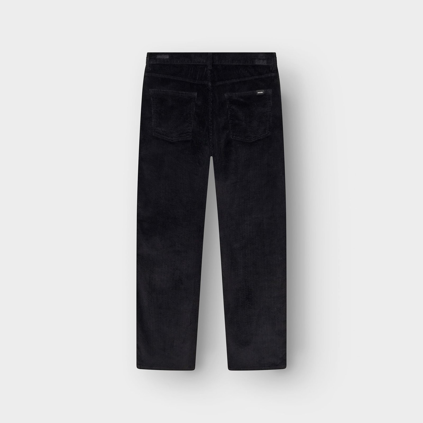 Back view of the Hamburg Corduroy Pants in black, laid flat to show the relaxed fit and back pockets.