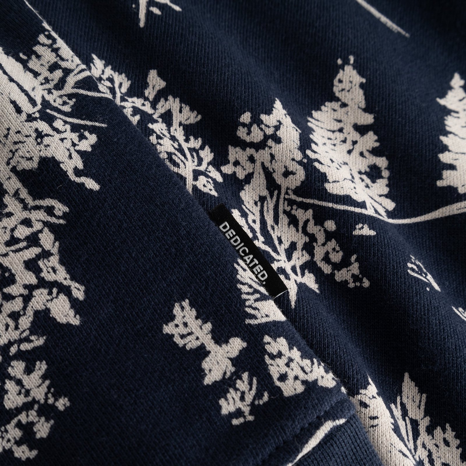 A close-up of the navy Blue Hills all-over-print sweatshirt, showing the detailed fabric and small Dedicated brand label.