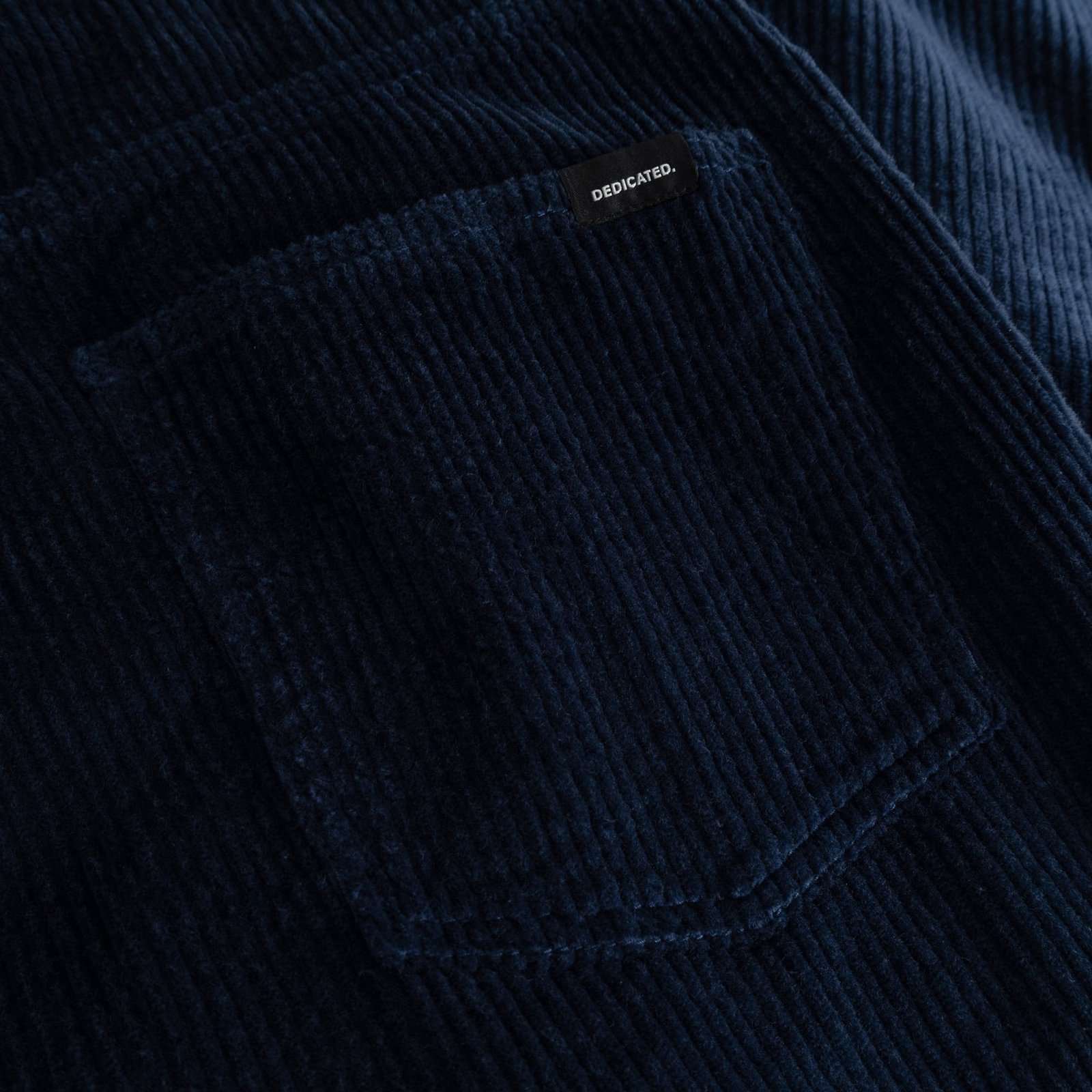 A detailed shot of the rich navy corduroy fabric on the Hamburg pants, with the Dedicated label on the back pocket.