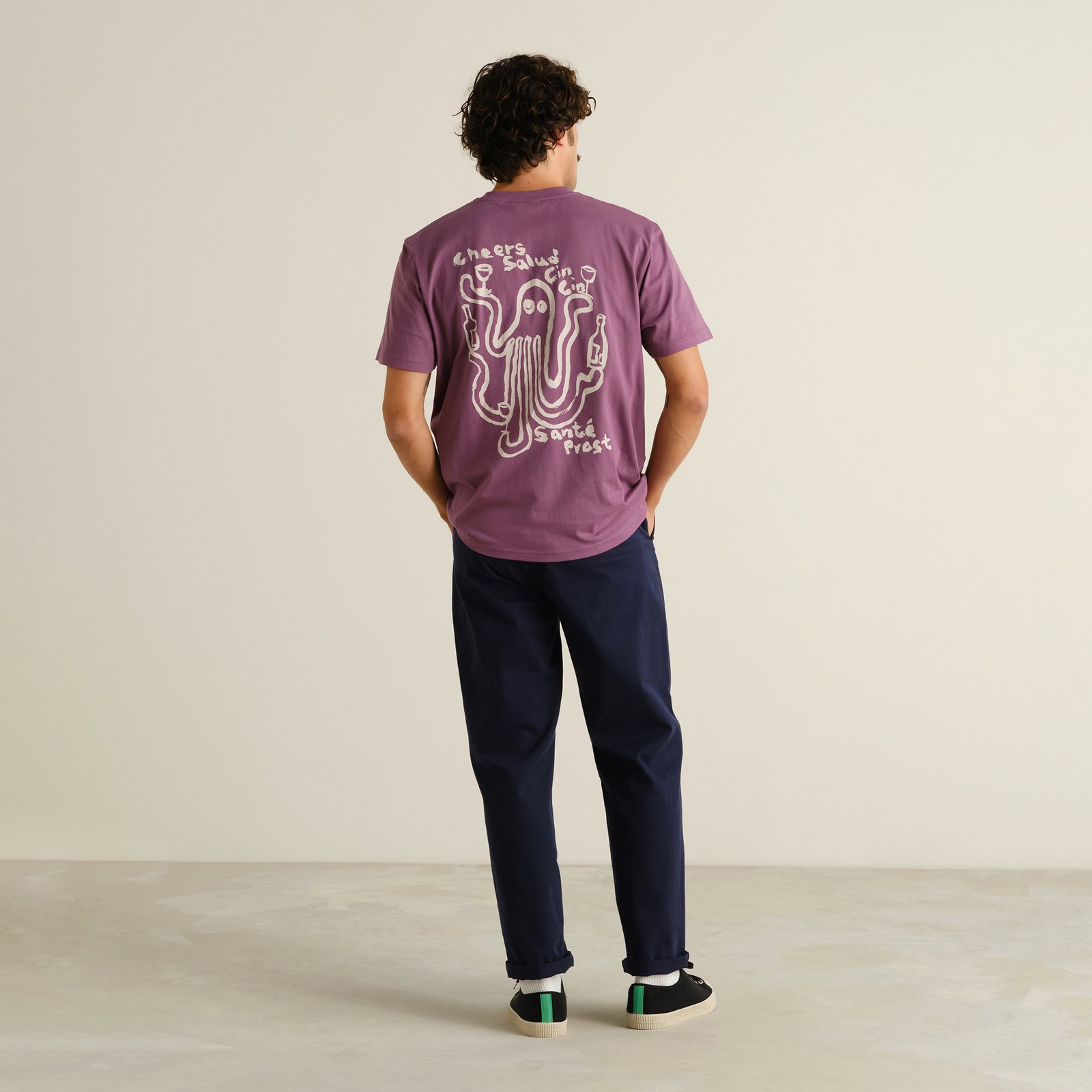 Back view of a man wearing the navy Chino Pants Hudiksvall, styled casually with a purple graphic t-shirt and black sneakers.