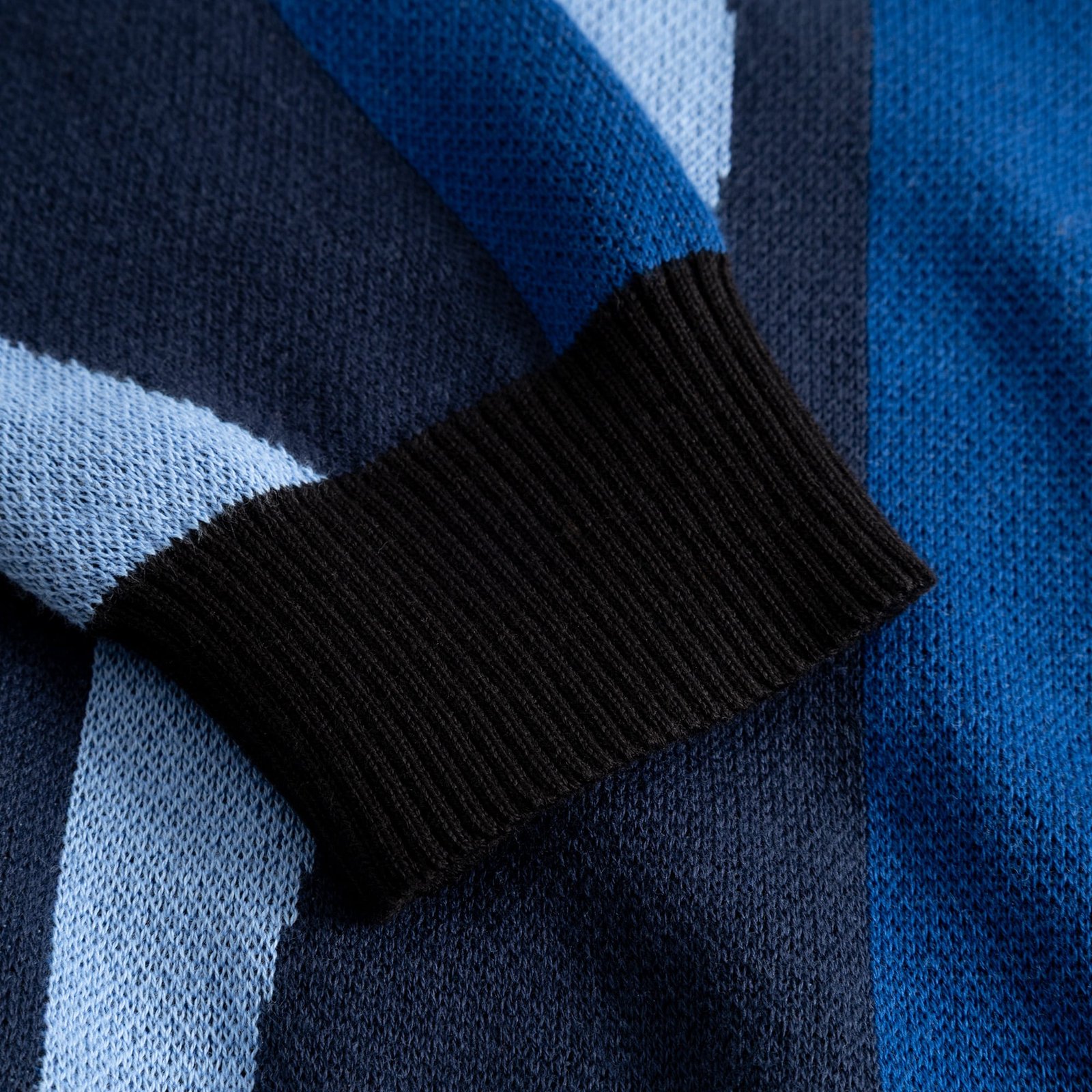 Close-up of the Sweater Arendal Wavy Stripe Blue showing the black ribbed cuff and detailed knit texture.