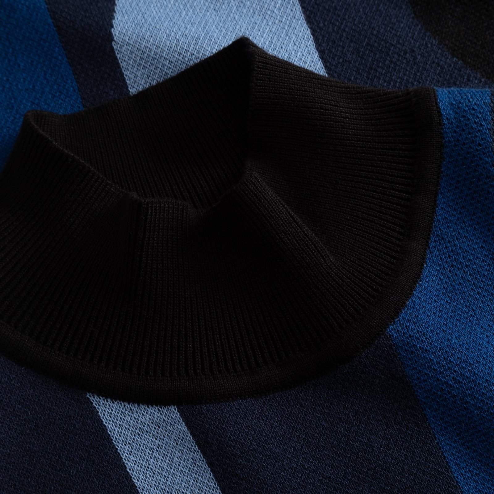 Close-up of the high ribbed collar on the Nikkala dress, showing the fine jacquard knit in wavy blue stripes.