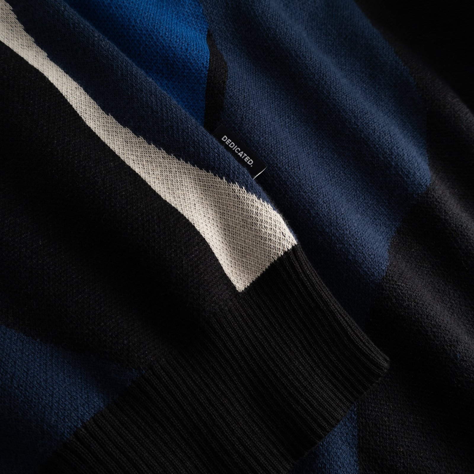 A close-up of the Sweater Mora Wavy Stripe Blue, highlighting the intricate jacquard knit, ribbed cuff, and brand label.