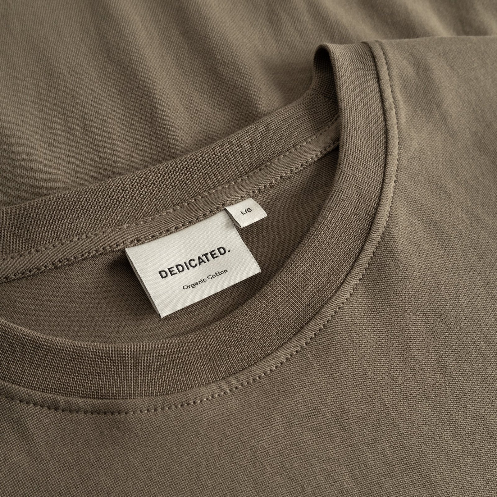 A close-up of the T-shirt Stockholm in Bungee Green, showing the ribbed neckline and the Dedicated brand label.