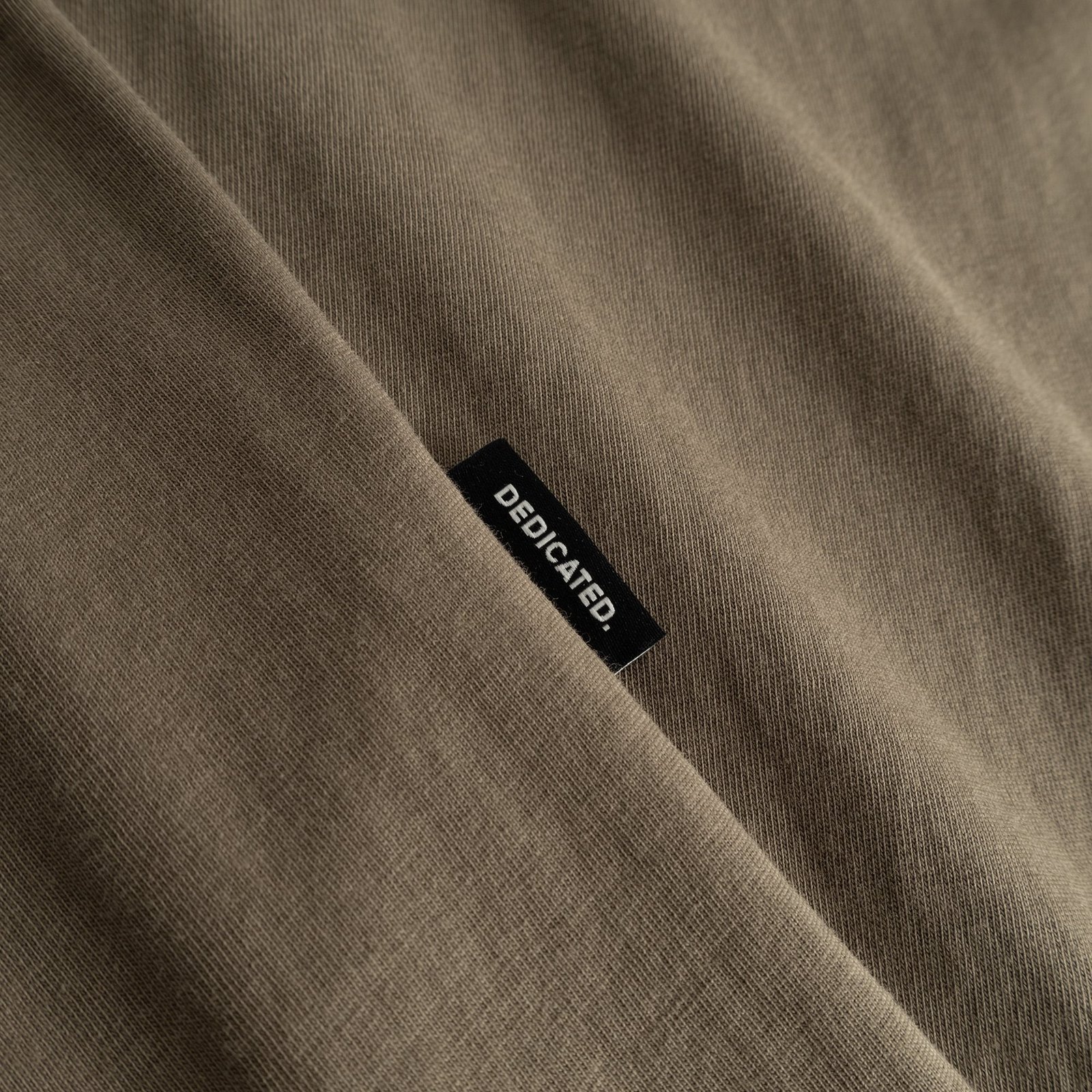 A close-up of the soft, Bungee Green fabric on the T-shirt Stockholm, featuring the Dedicated brand label.