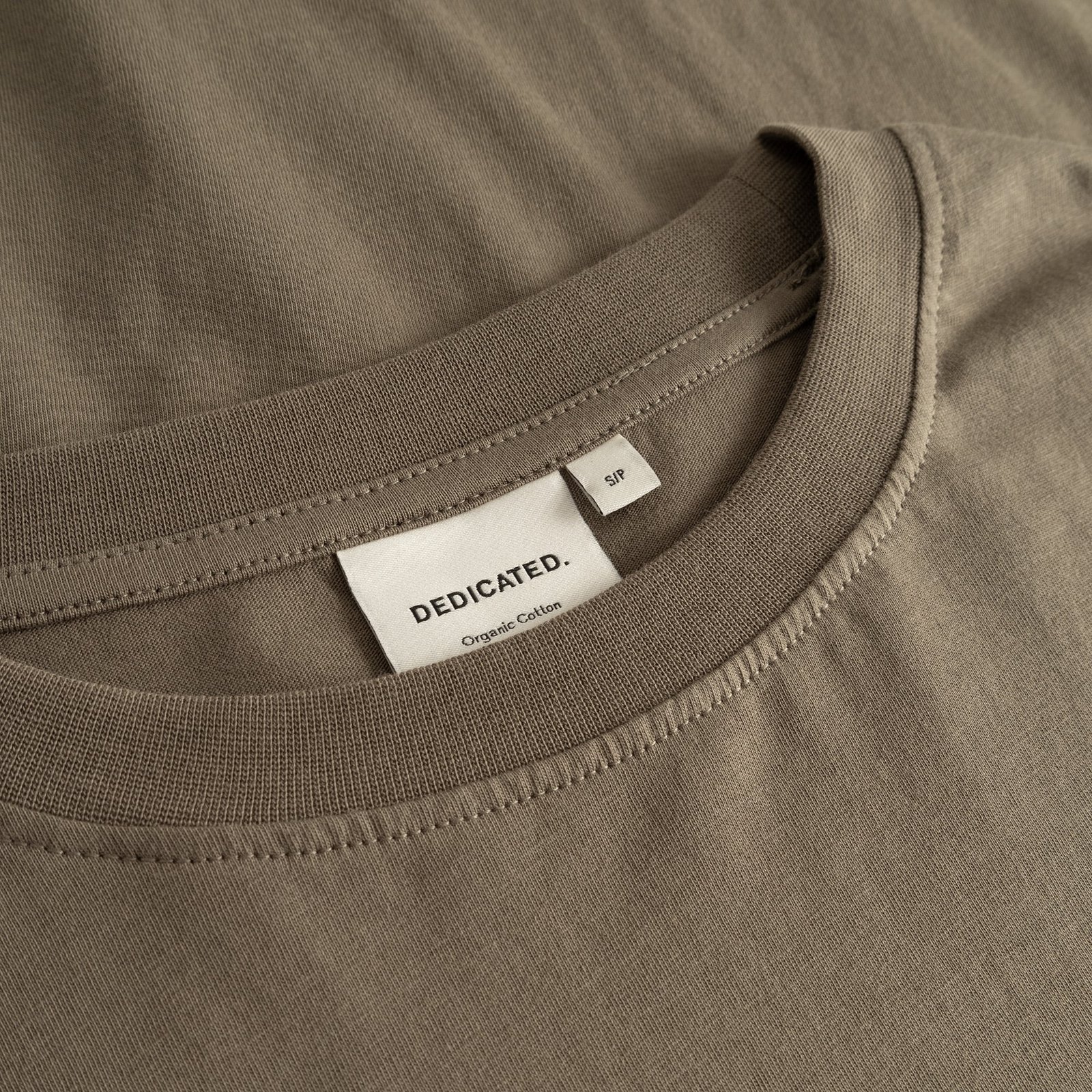 A detailed close-up of the ribbed crew neck and brand label on the T-shirt Vadstena Base in a versatile Bungee Green.