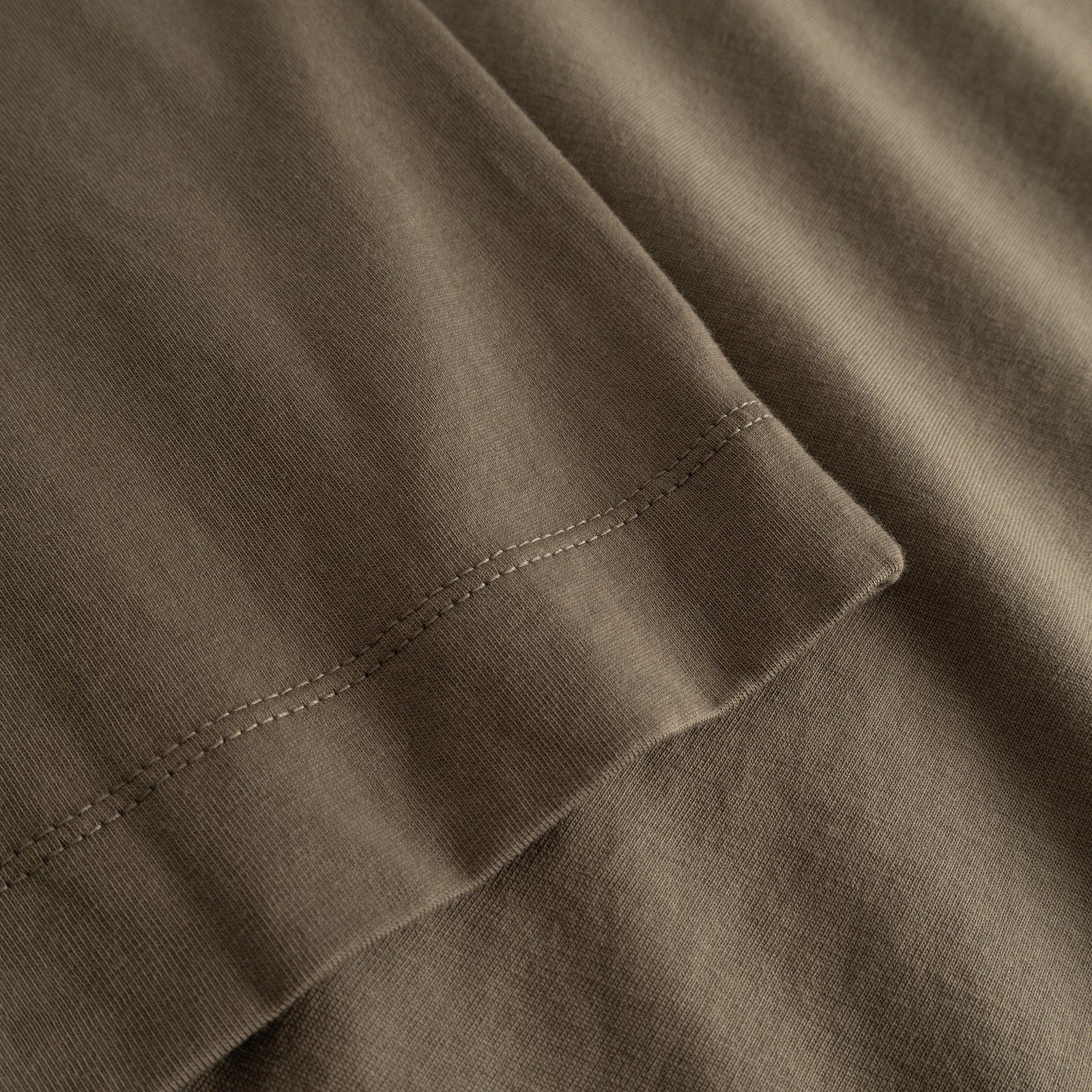 Detailed shot of the Vadstena Base T-shirt's sleeve in Bungee Green, showcasing its soft fabric and quality stitching.