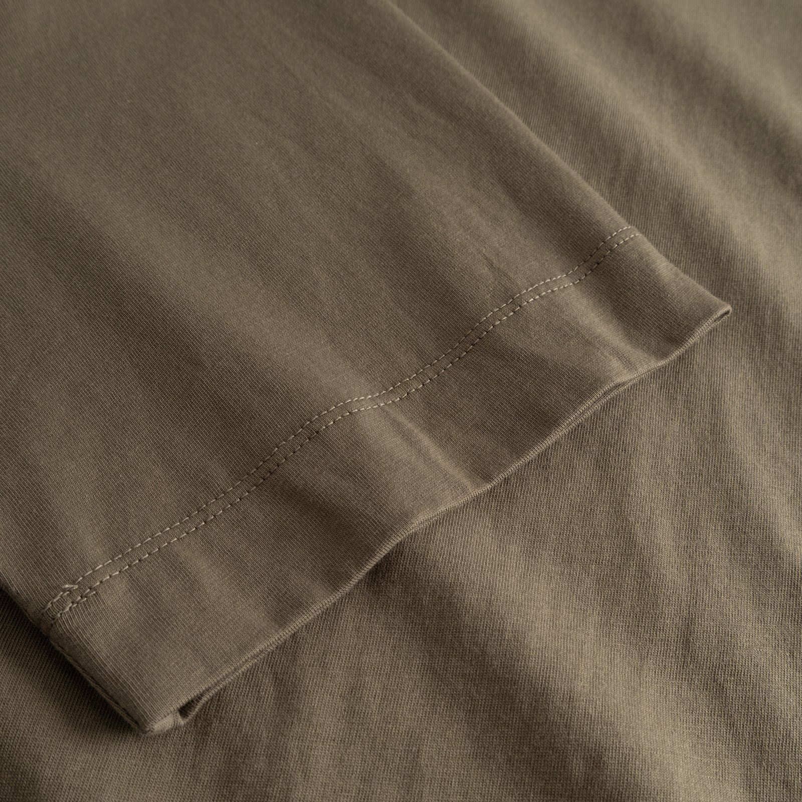 A detailed close-up of the sleeve on the T-shirt Vadstena Base in Bungee Green, showing the fine stitching and fabric.