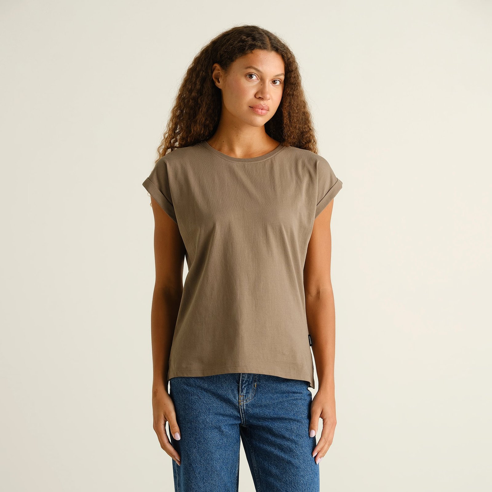 Front view of a woman wearing the T-shirt Visby Base in Bungee Green, styled with a pair of classic blue jeans.