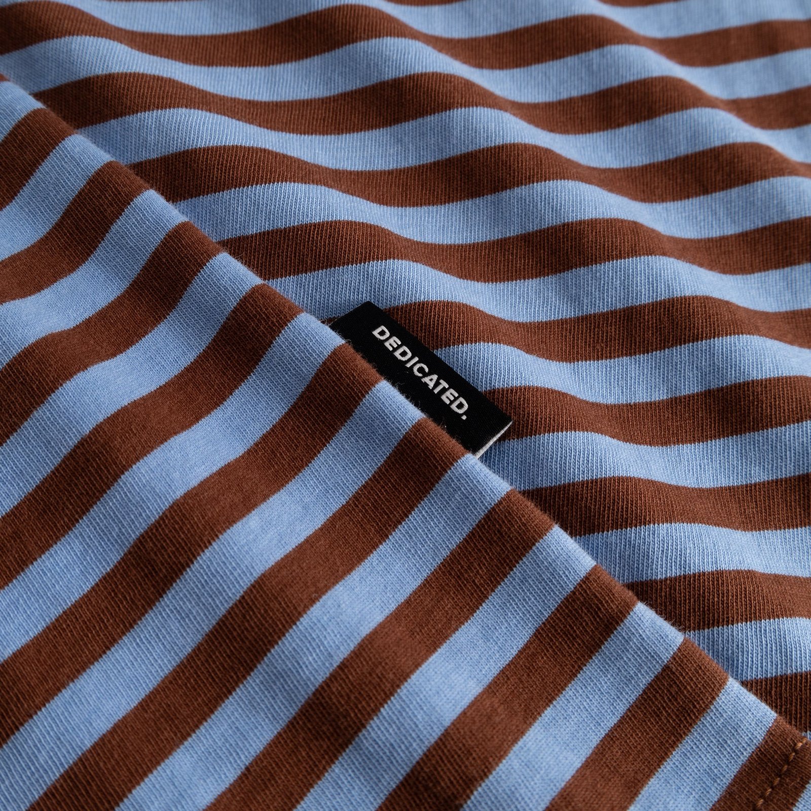 Close-up of the striped T-shirt Stockholm in cappuccino brown and cornflower blue, showing the soft fabric and brand tag.