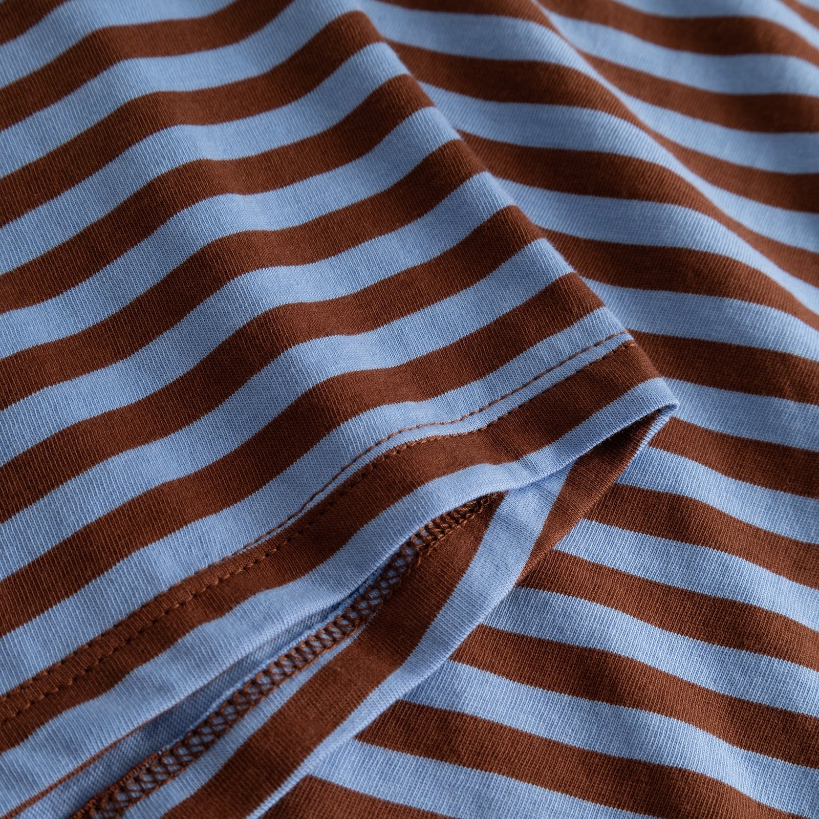 Close-up of the yarn-dyed stripes in cappuccino brown and cornflower blue on the soft organic cotton Top Humledal.
