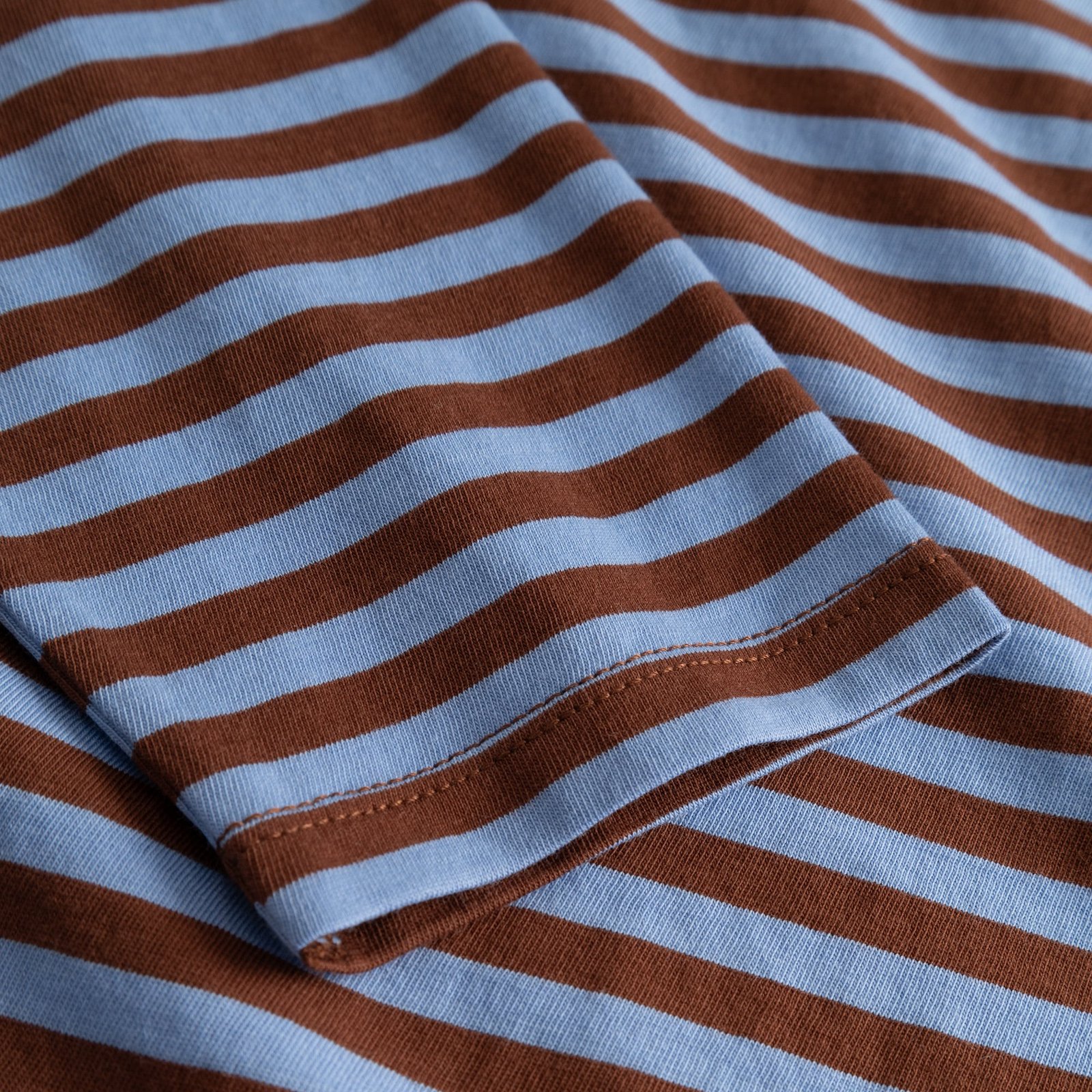 Close-up of the sleeve on the Top Humledal, showing the cappuccino brown and cornflower blue striped organic cotton fabric.