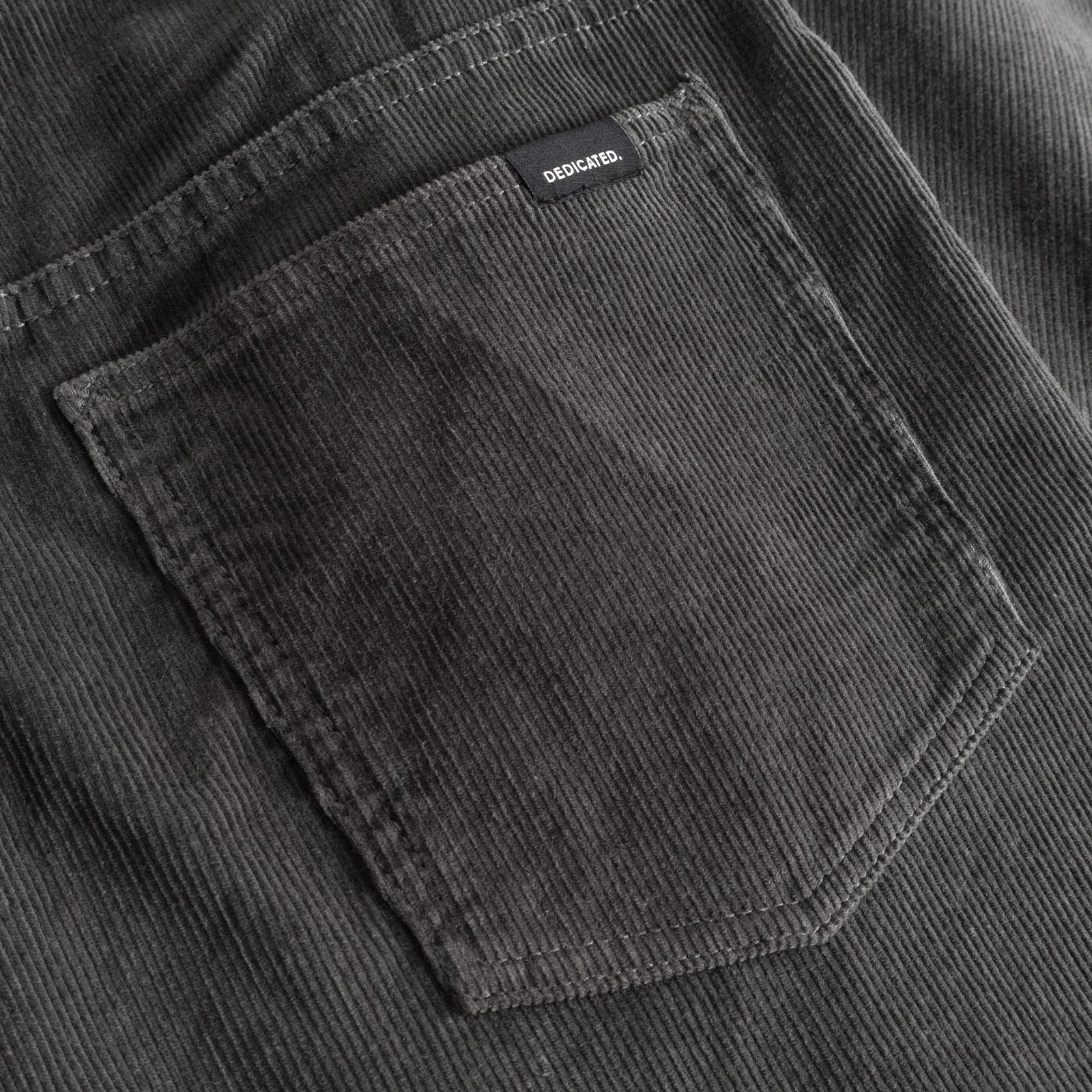 Detailaufnahme der Gesäßtasche der Cordhose Ryda in Rock Grey, die die klassische Textur und das Dedicated Label zeigt.