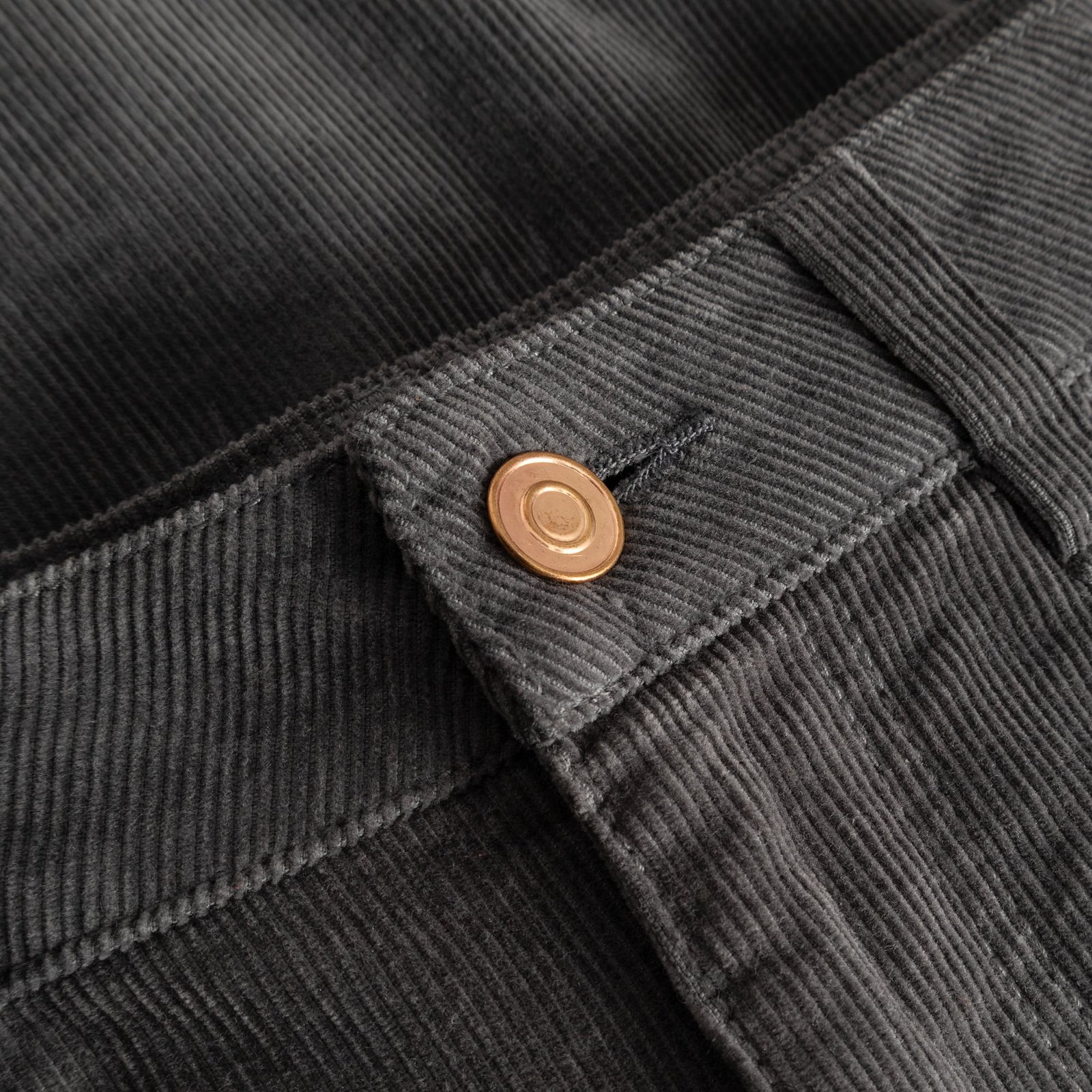 Detailaufnahme des Cordstoffs in Rock Grey und des Knopfes am Bund der Hose Ryda.