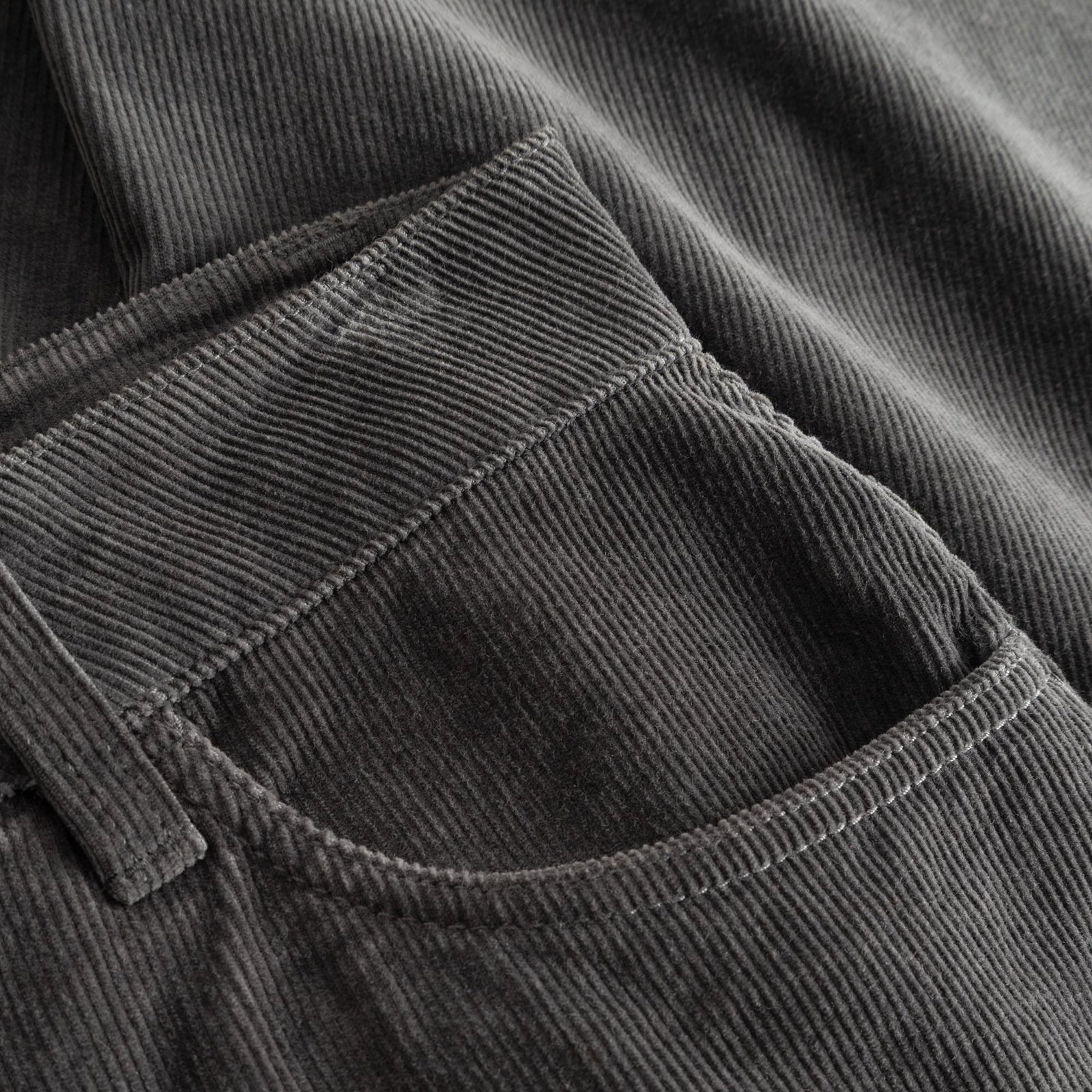 Nahaufnahme der Vordertasche und der feinen Rippenstruktur der Cordhose Ryda in Rock Grey.