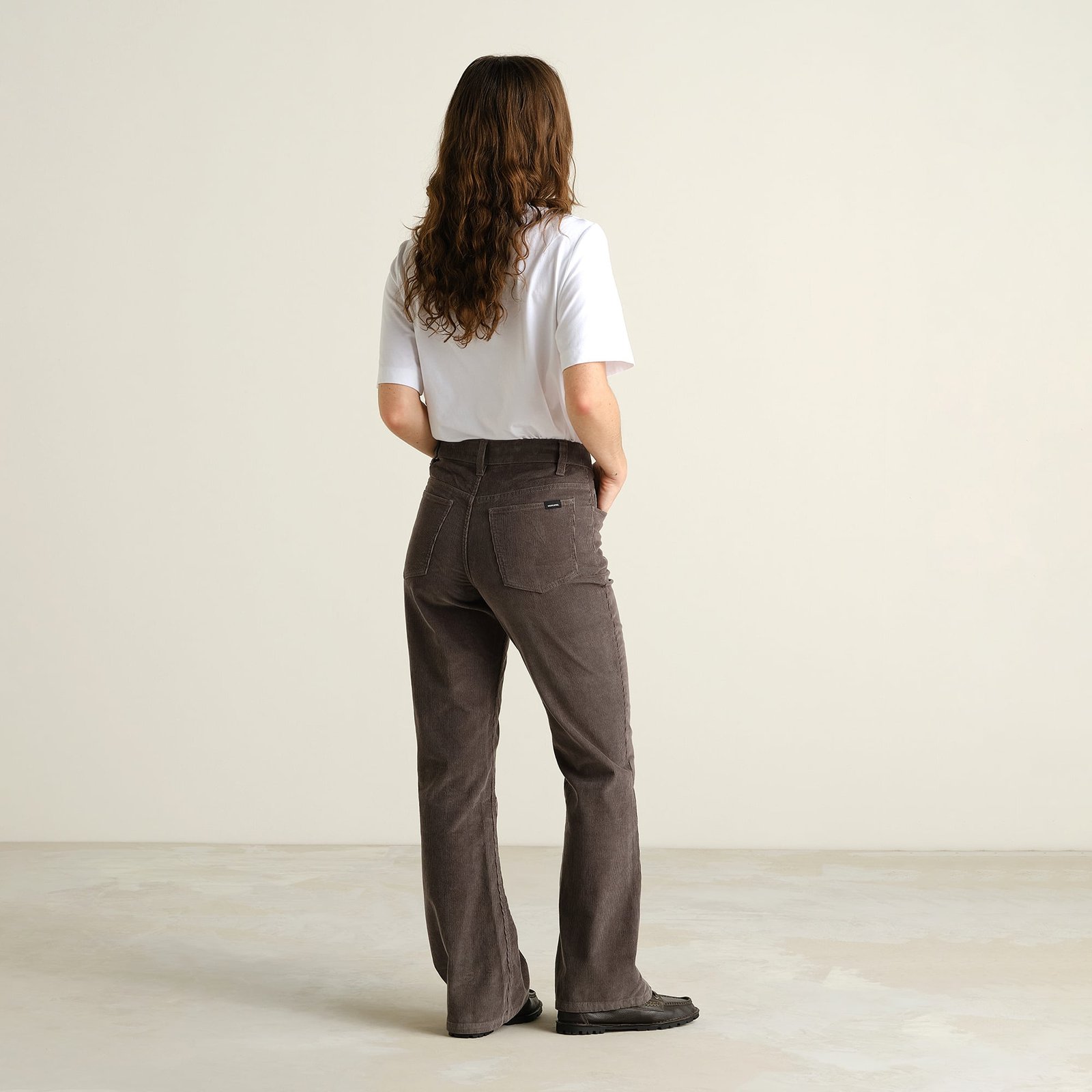 Rückansicht einer Frau, die die Bootcut-Cordhose Ryda in Rock Grey trägt.