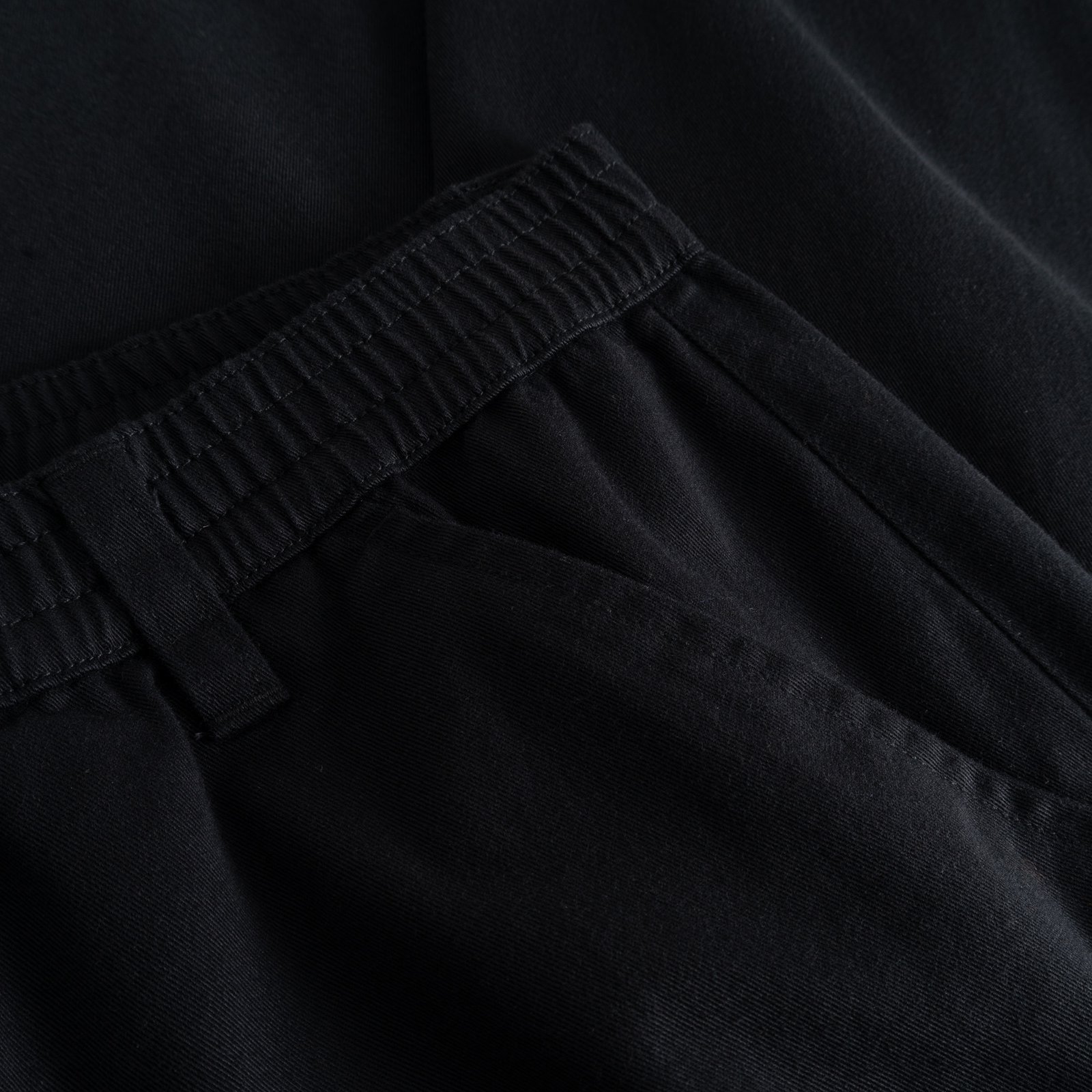 A detailed look at the elasticated waistband of the black Hudiksvall Chino Pants, crafted from organic cotton twill.