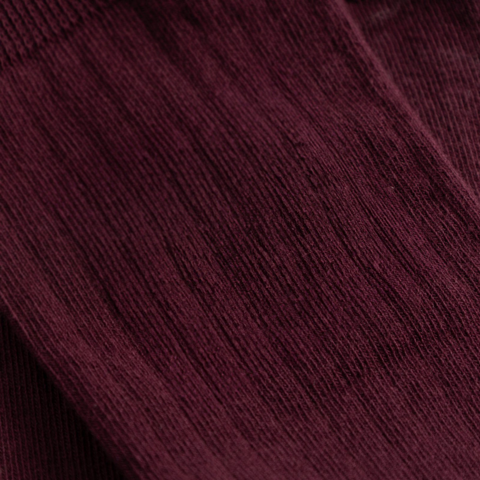 Close-up detail shot of the Rib Socks Knivsta, showing the fine ribbed texture in a deep Fig Red color.