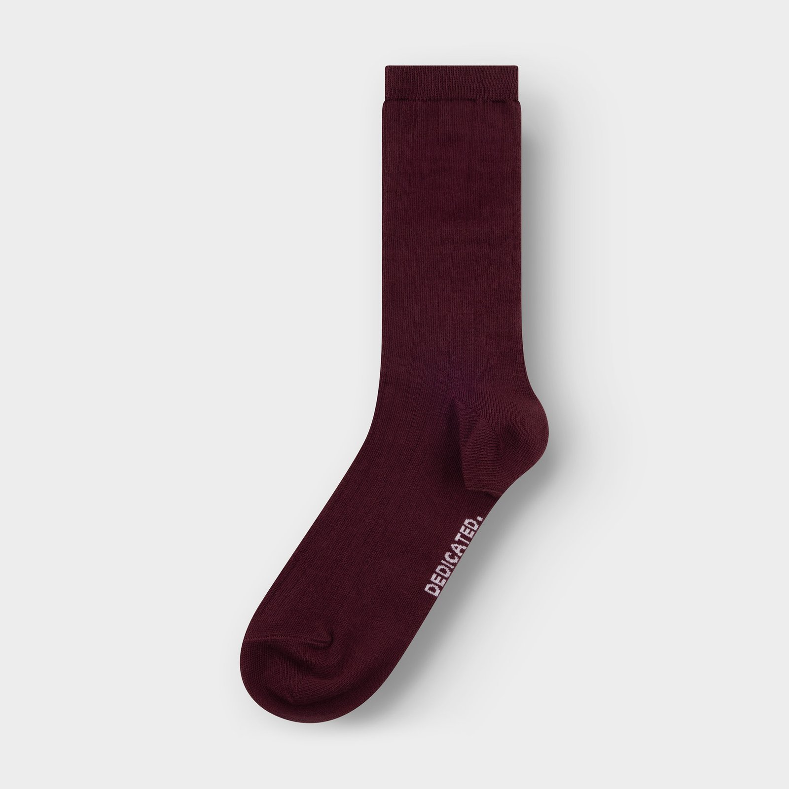 A single Dedicated Rib Sock Knivsta in fig red, laid flat against a plain light grey background.