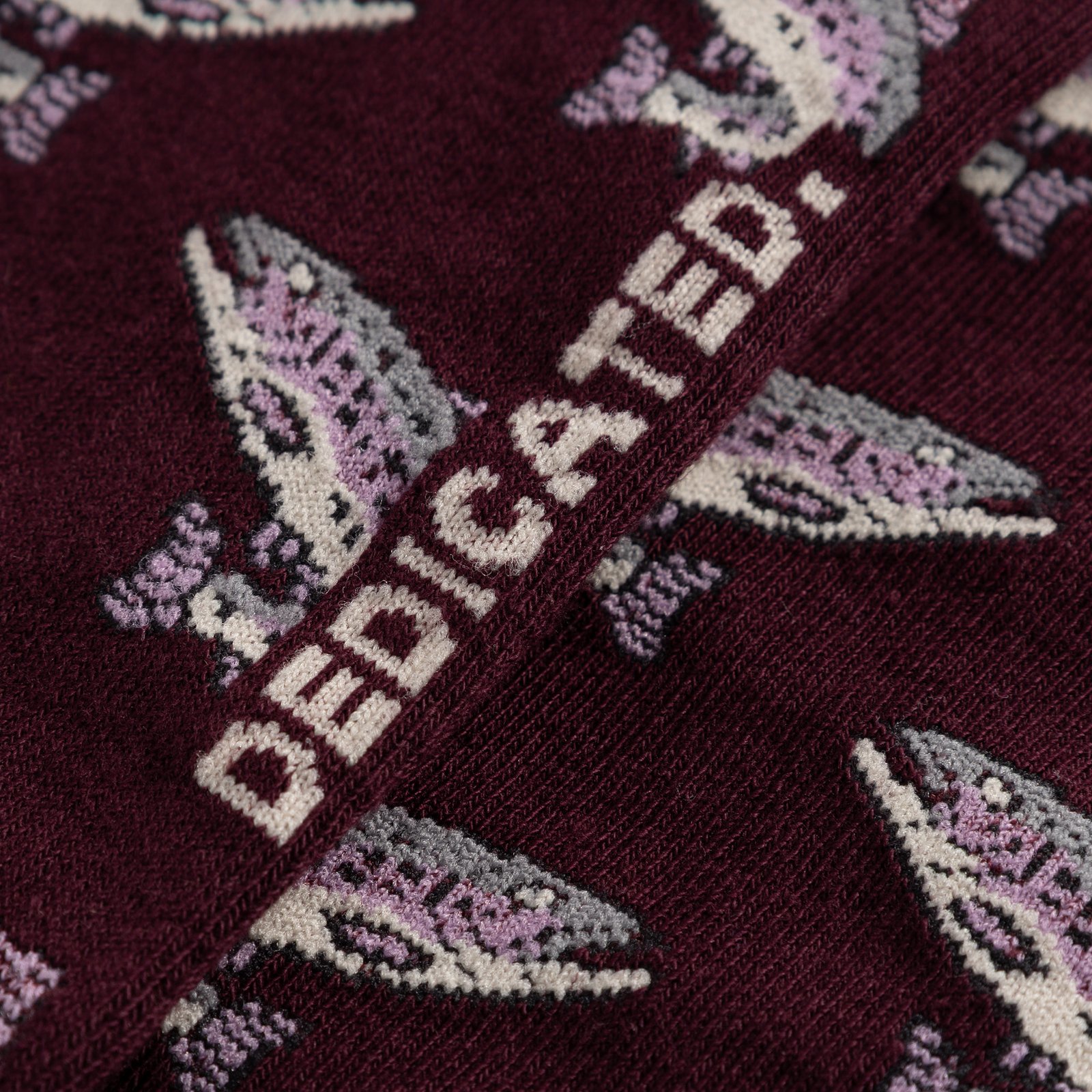 A close-up shot of the Dedicated Sigtuna socks in fig, showing the detailed jacquard knit of the fun trout pattern.