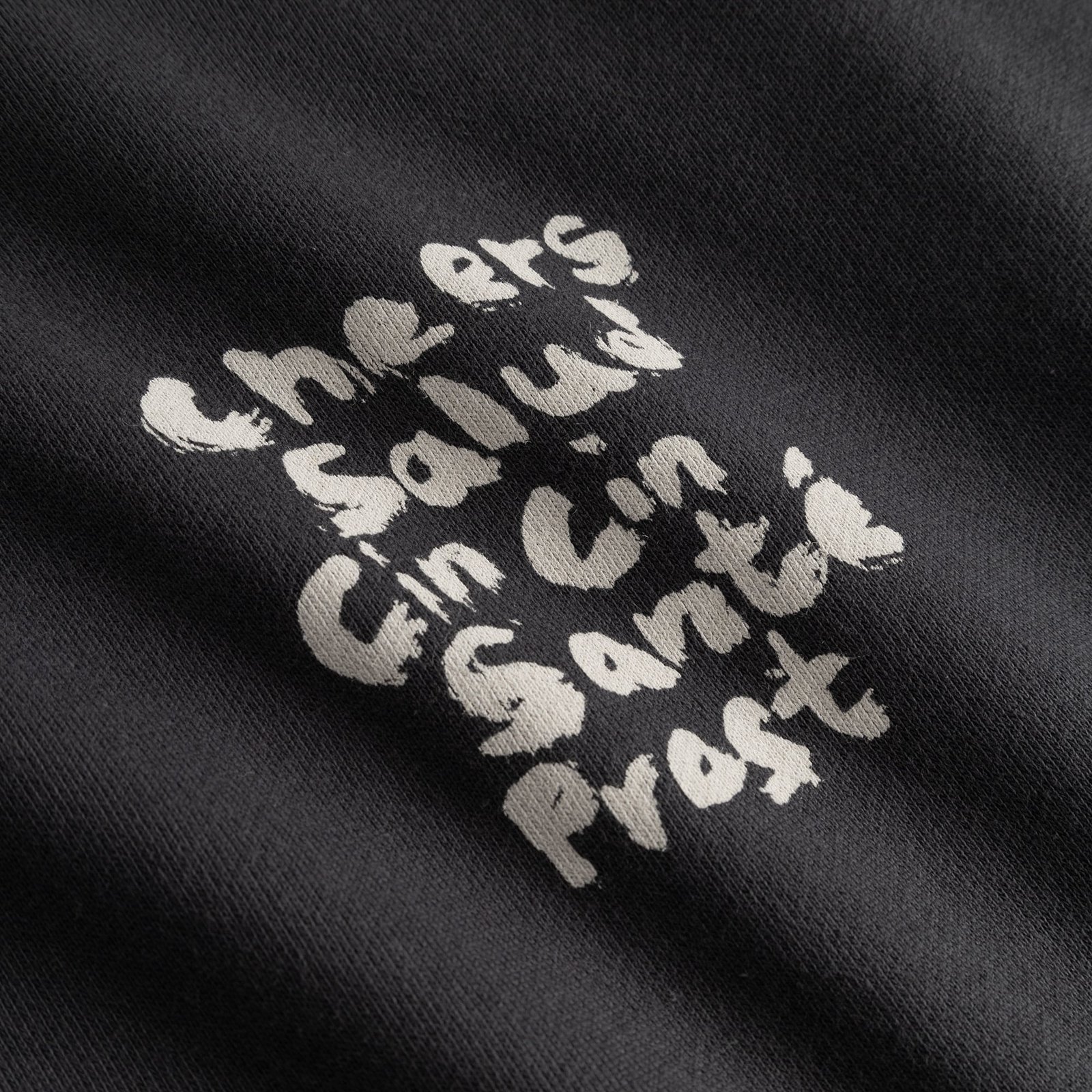 Close-up of the 'Cheers Salud' print in a textured, brush-stroke style on the charcoal Malmoe sweatshirt.