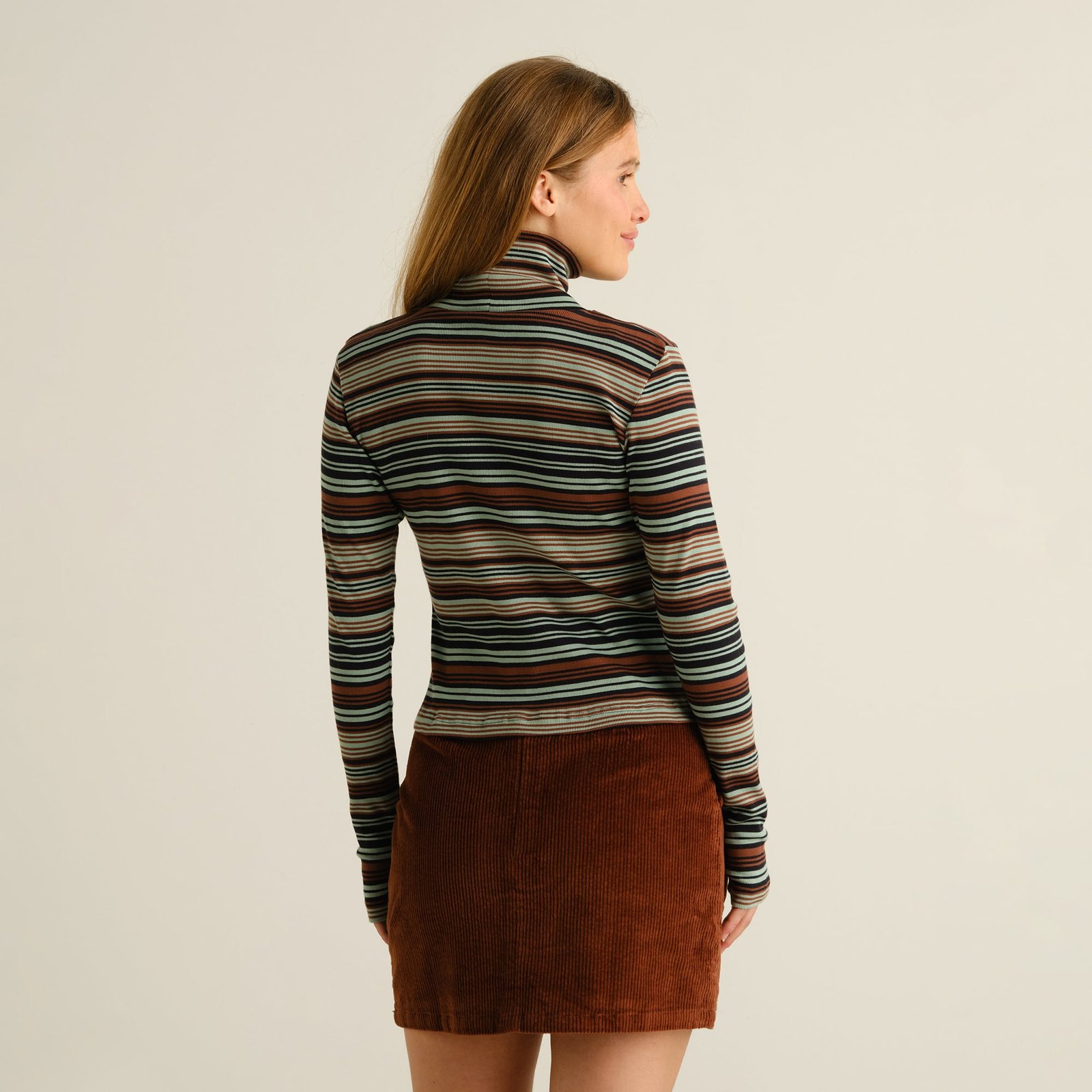 Model seen from behind wearing the striped Rib Top Malma in green paired with a brown corduroy mini skirt.