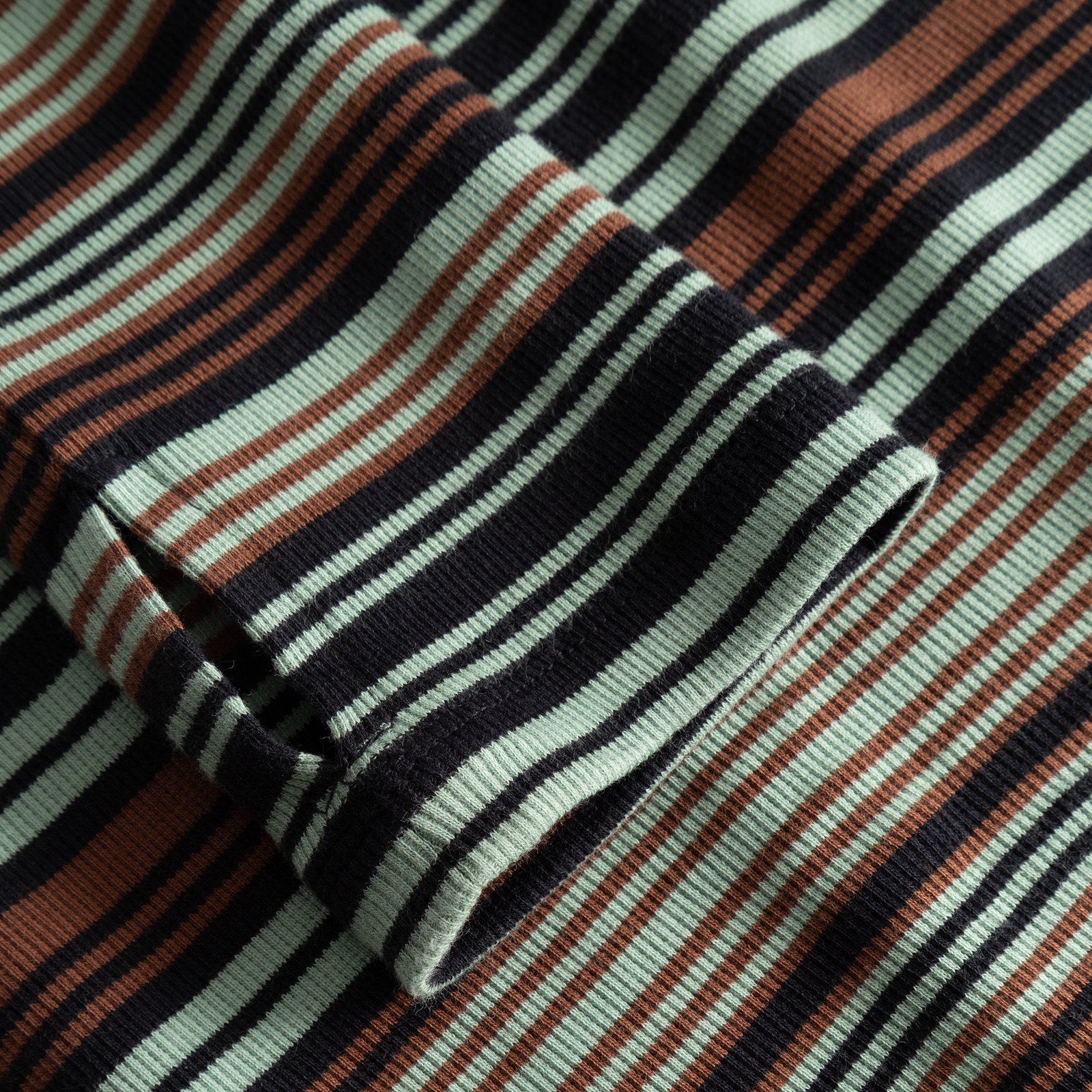 Close-up of the ribbed sleeve on the Lunsen Dress, showing the thumbhole and green, brown, and black irregular stripes.