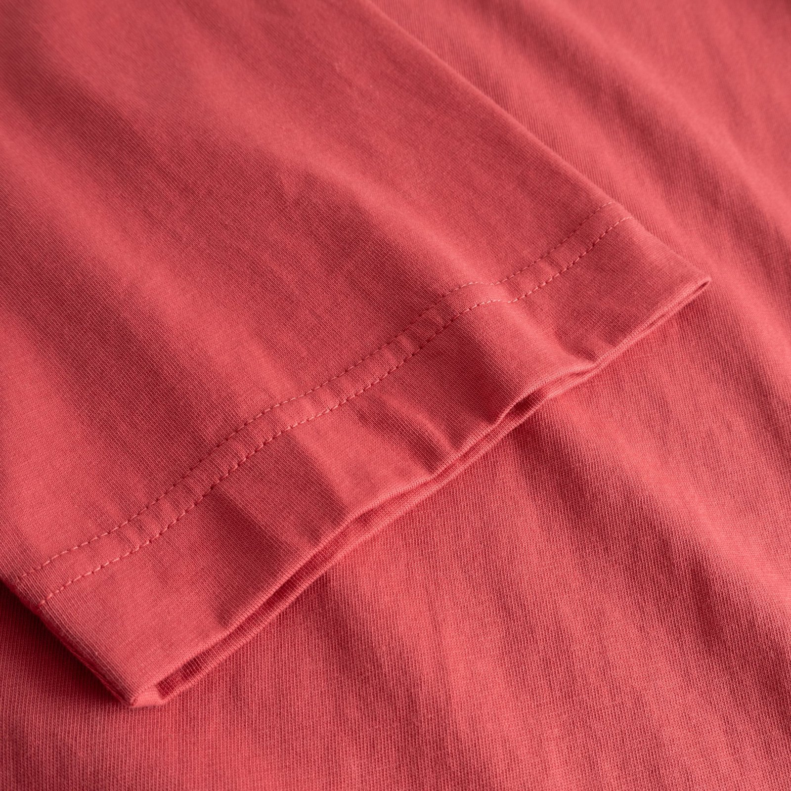 A close-up view of the sleeve hem on the T-shirt Vadstena Paws For a Moment in Holly Red, showcasing the soft fabric.